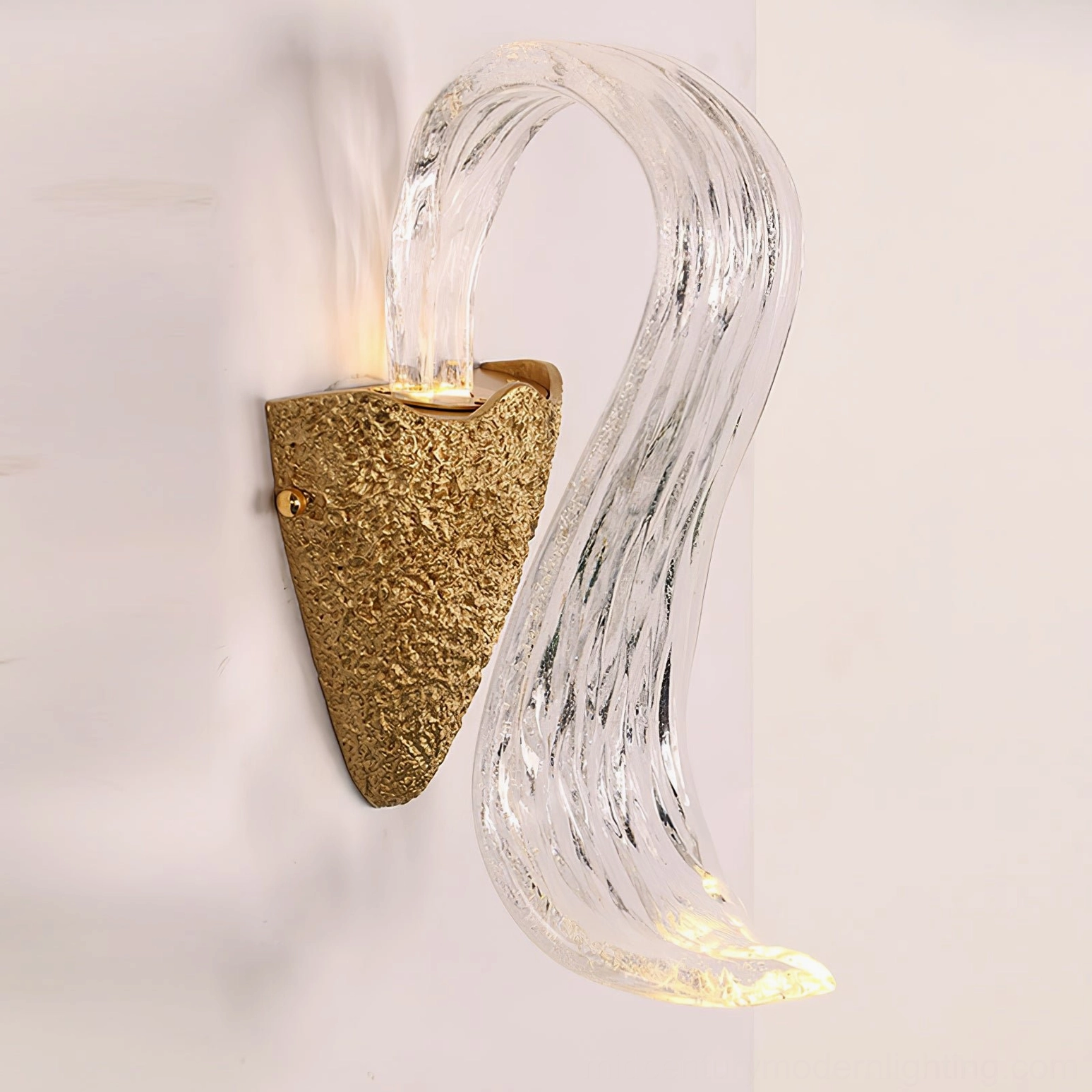 Icarus curved fluid glass wall lamp with hammered gold base illuminated with warm ambient light