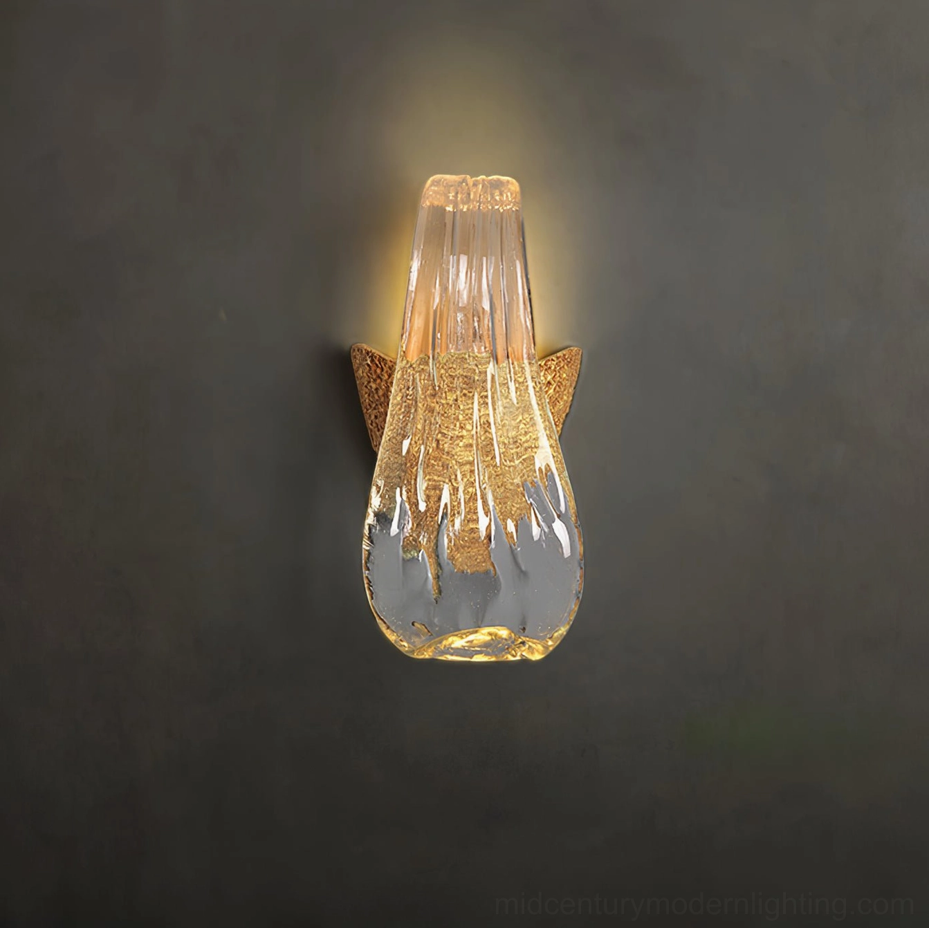 Icarus droplet glass wall lamp illuminated with warm light against dark gray wall showing textured glass detail
