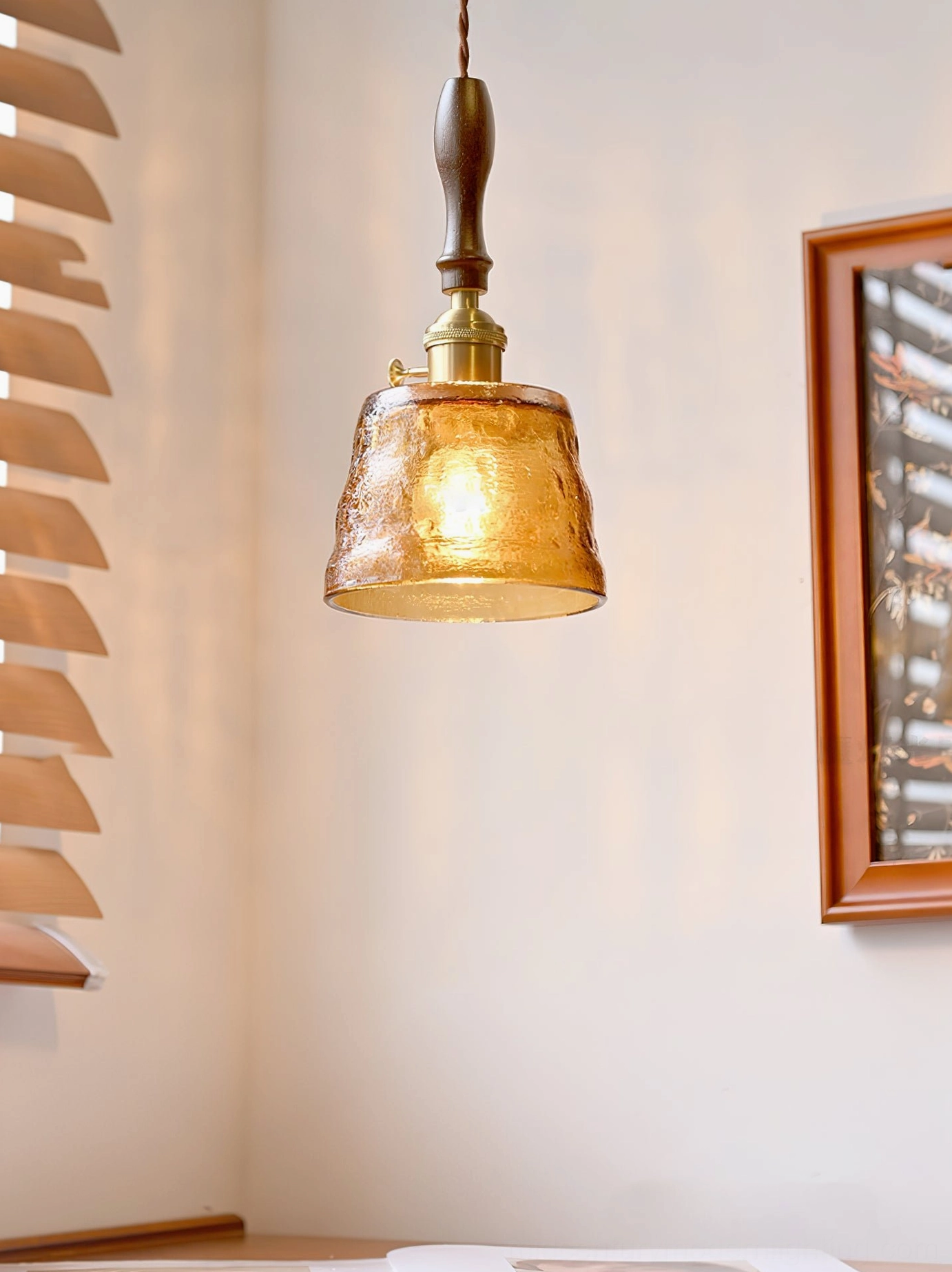 Jace pendant lamp with warm amber glass shade illuminated in modern interior design setting