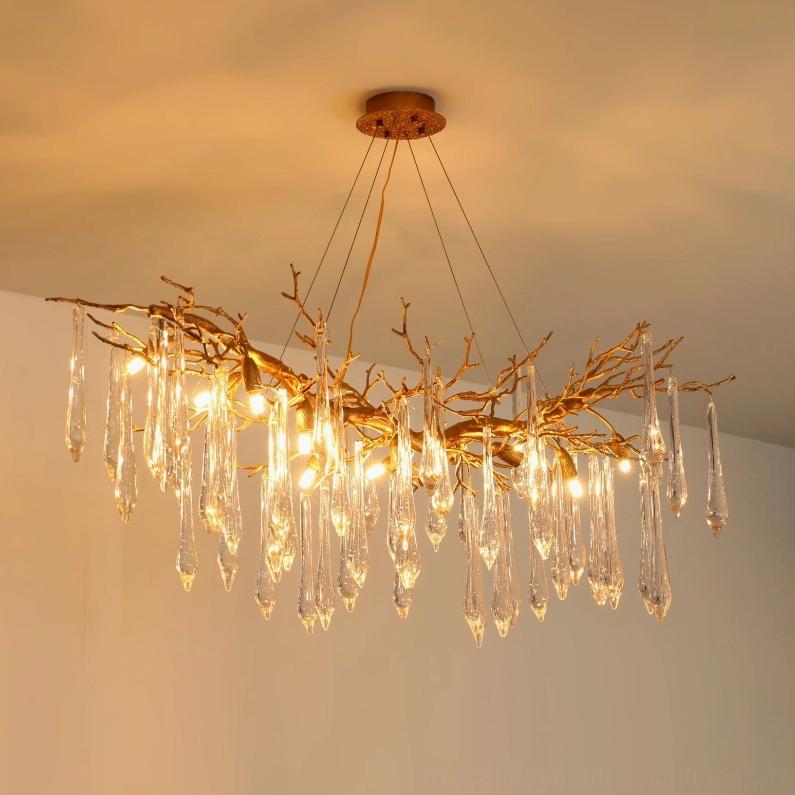 Janae branch chandelier side view with evenly distributed lit bulbs and crystal pendants against warm beige ceiling