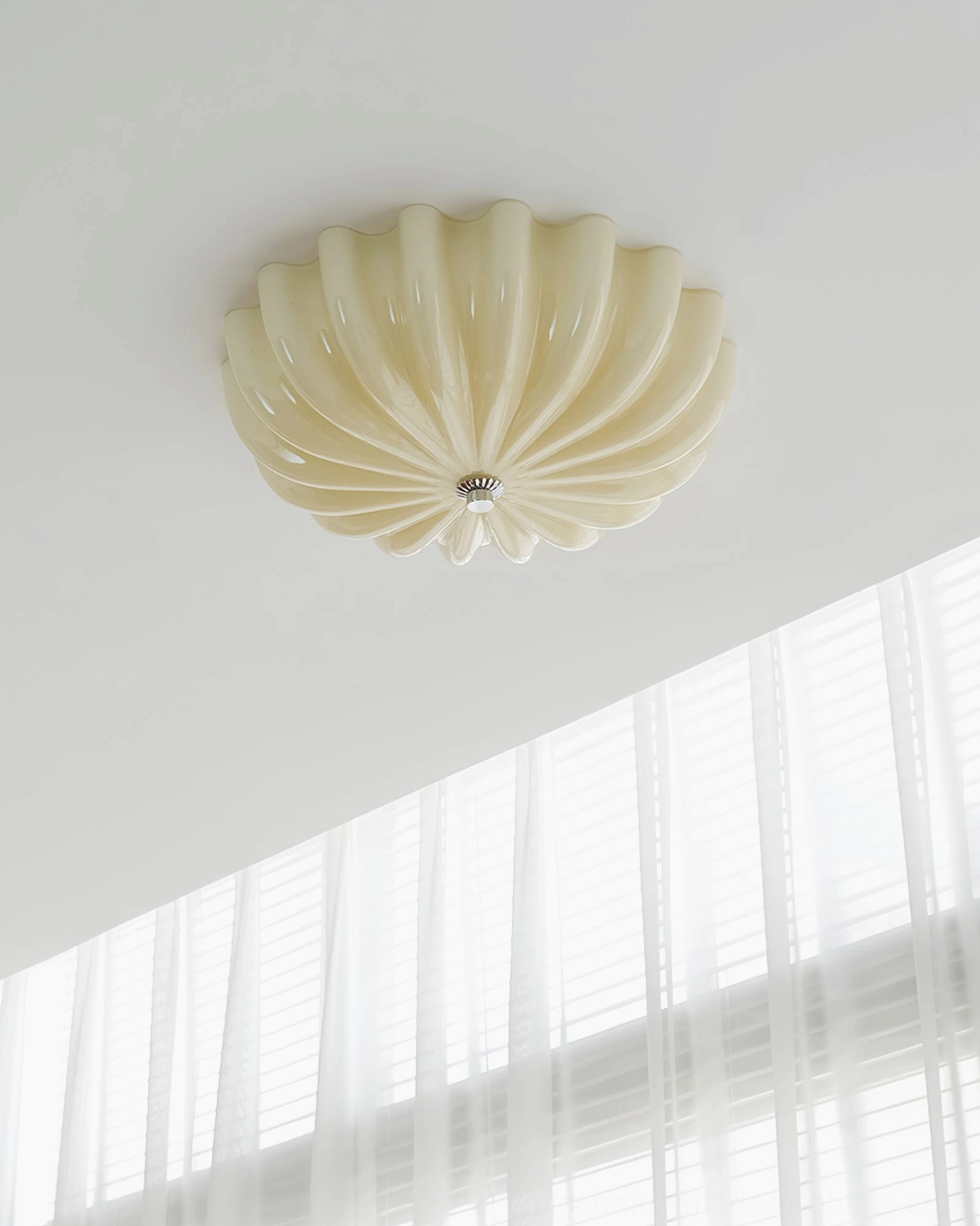 Jelly cream glass ceiling lamp mounted in bright room with sheer curtains, daytime appearance
