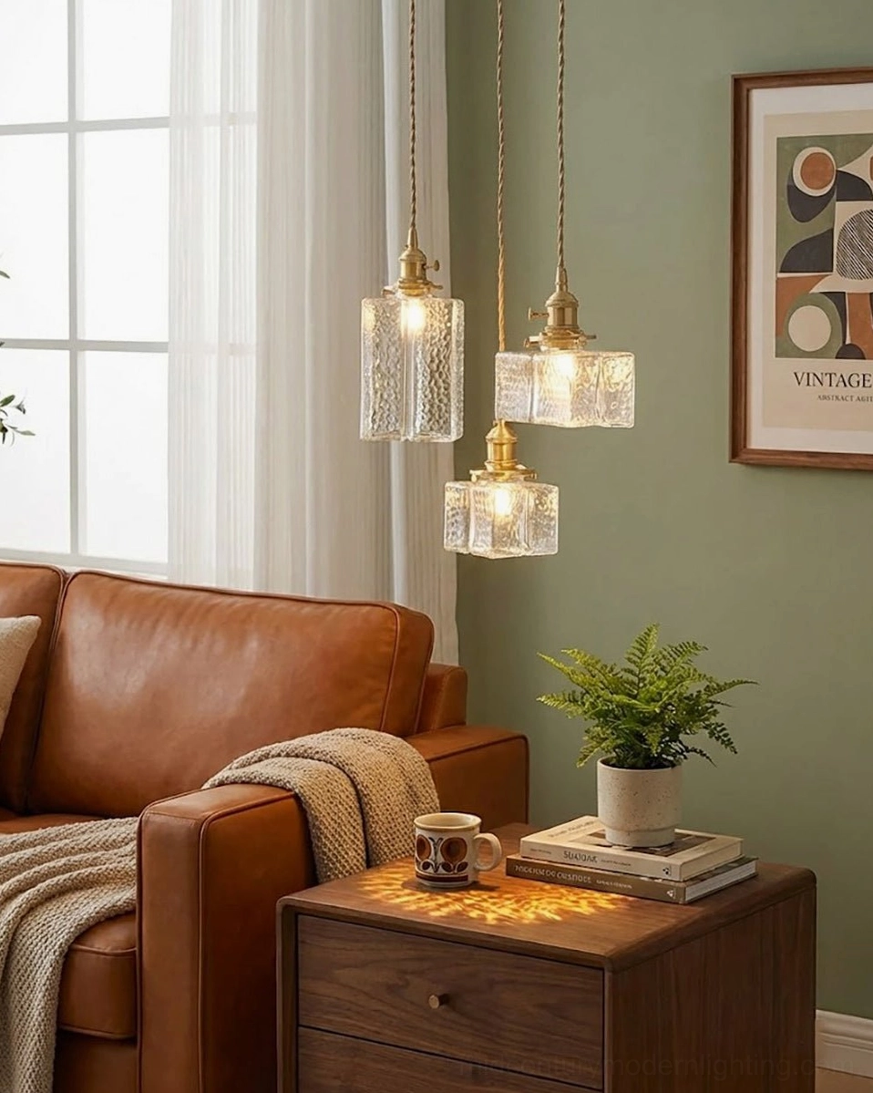 Trio of jewel brass pendant lights in green wall living room with brown leather seating and warm vintage aesthetic
