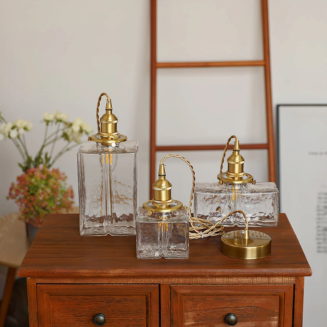 Multiple jewel brass pendant lights installed at varying heights above kitchen island in modern mid-century kitchen design