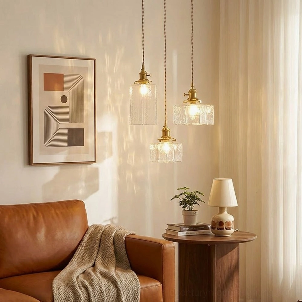Three jewel brass pendant lights installed above mid-century modern living room with leather sofa and vintage furnishings