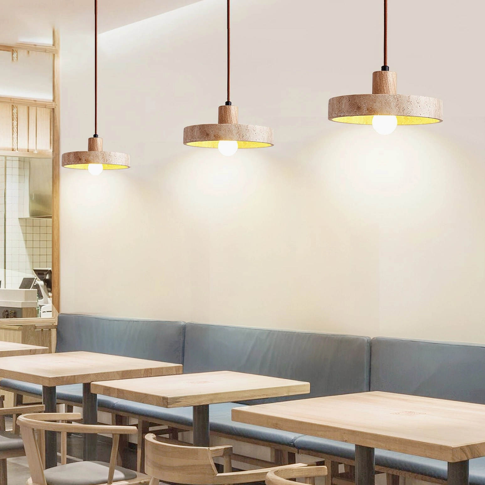 Three Kairi travertine stone pendants installed above cafe dining tables commercial space lighting
