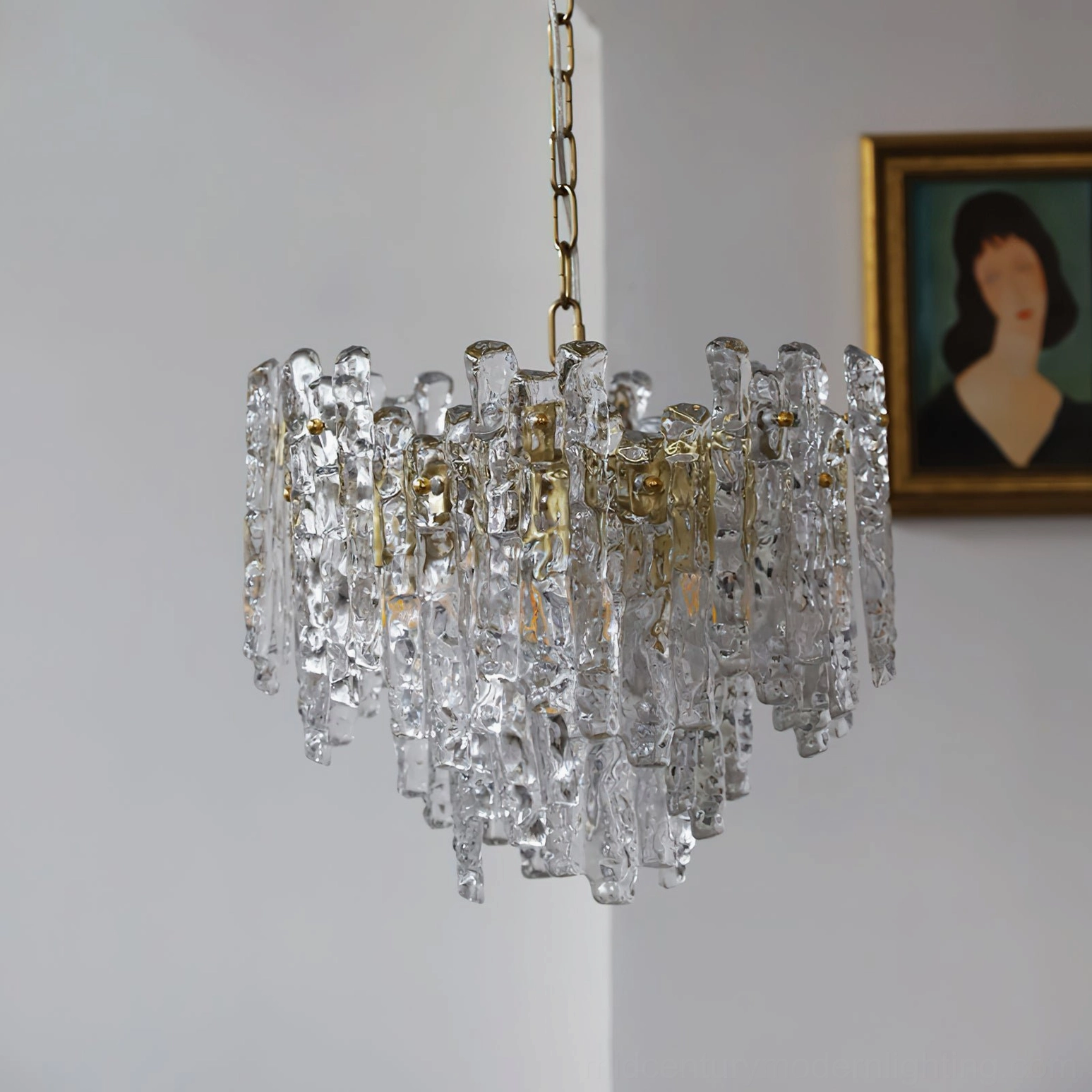 Kalmar clear textured glass pendant light with gold brass suspension chain hanging against minimalist wall with modern art