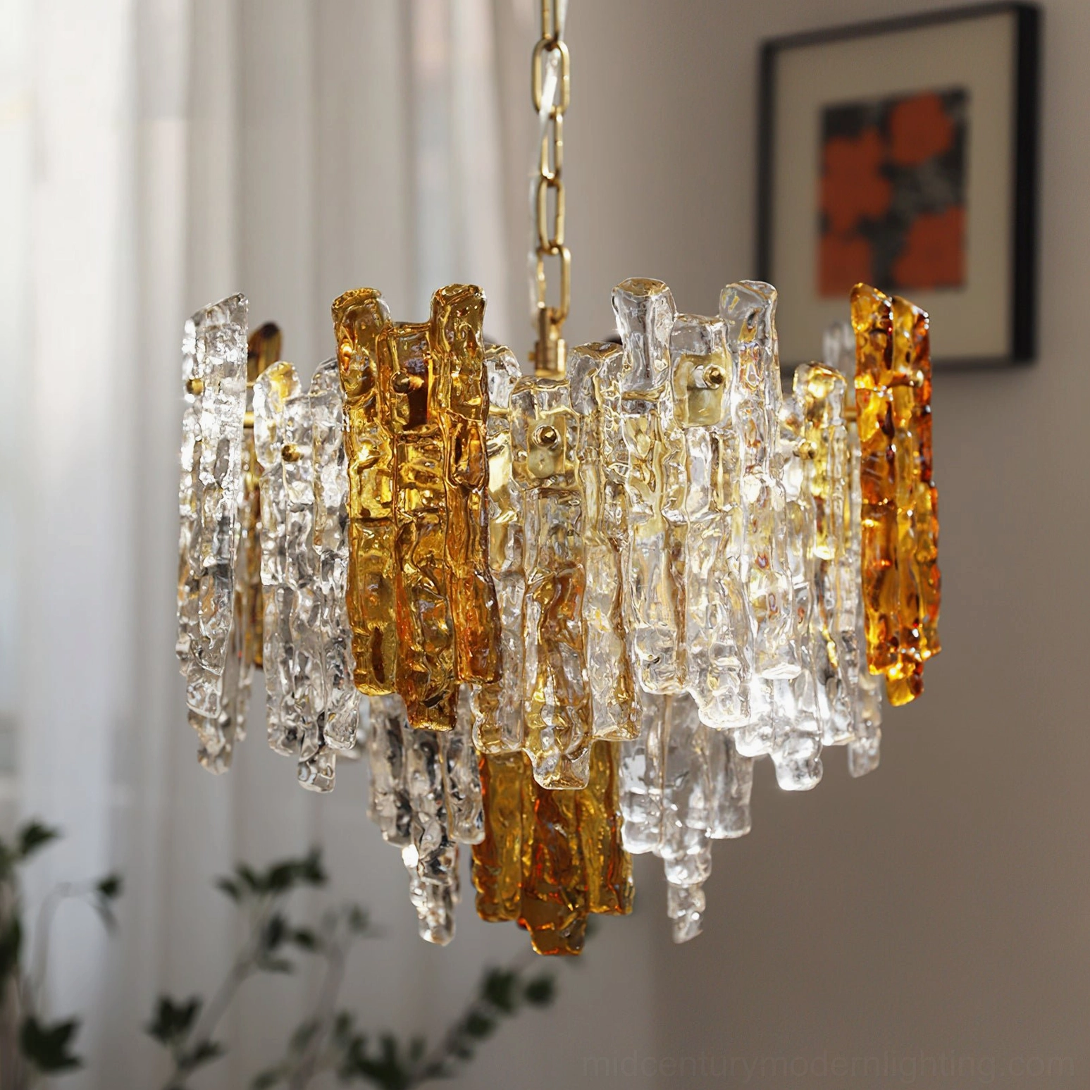 Kalmar dual-tone ice glass pendant chandelier hanging in warm living room with amber and clear layered glass creating ambient light