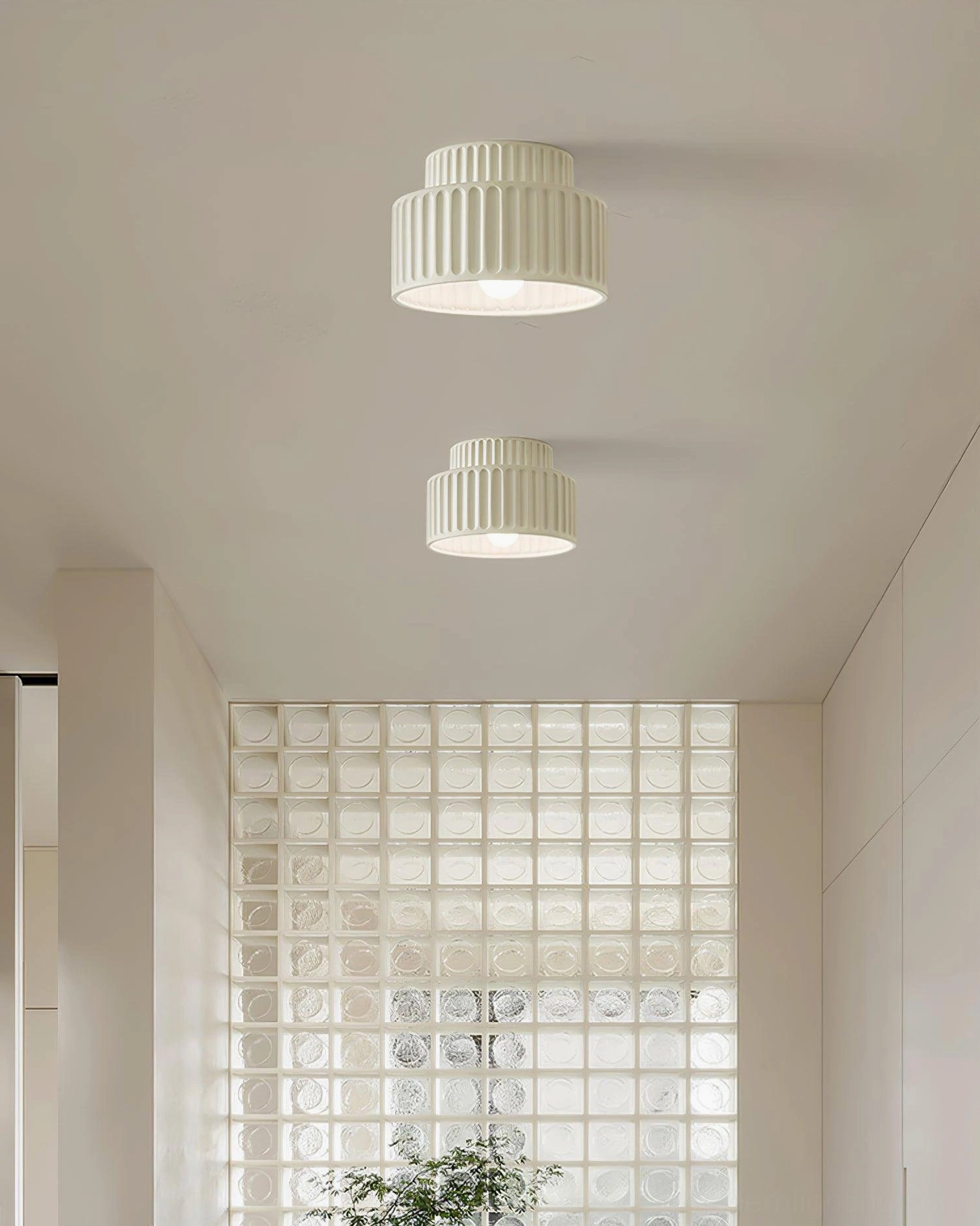 Two off-white Kami ceiling lamps installed in modern stairwell with glass block window and neutral décor