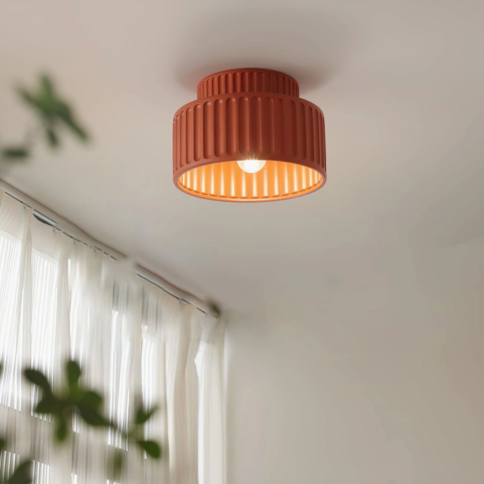 Kami flush mount ceiling light installed in minimalist living room with sheer curtains and green plants, warm ambient lighting