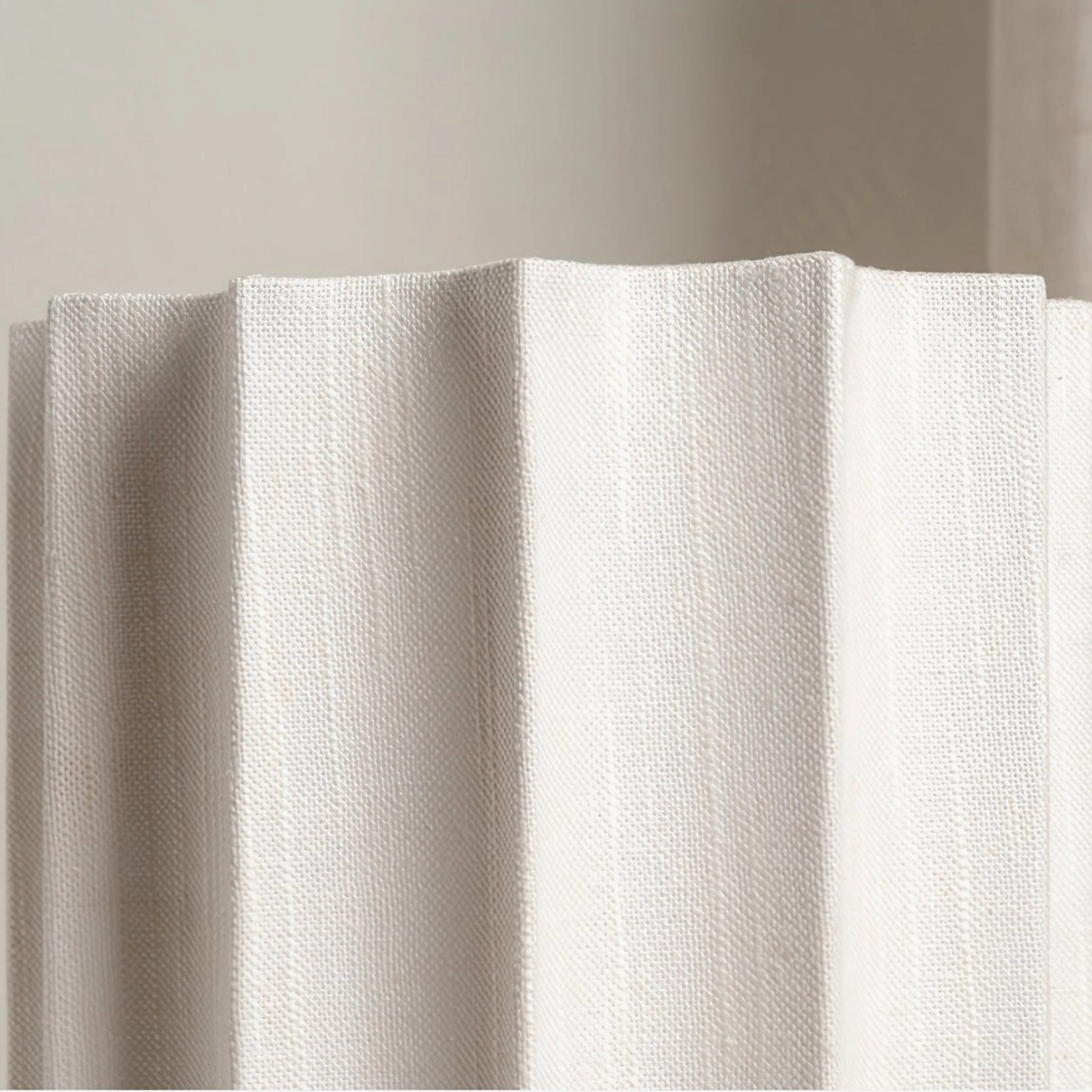 Close-up detail of Kane lamp's cream-colored linen pleated fabric shade texture on neutral background