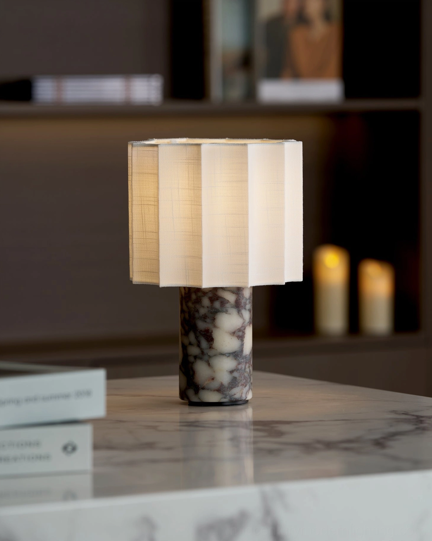 Kane portable lamp illuminated on marble countertop, beige pleated shade with warm LED glow and dark-veined Calacatta marble base