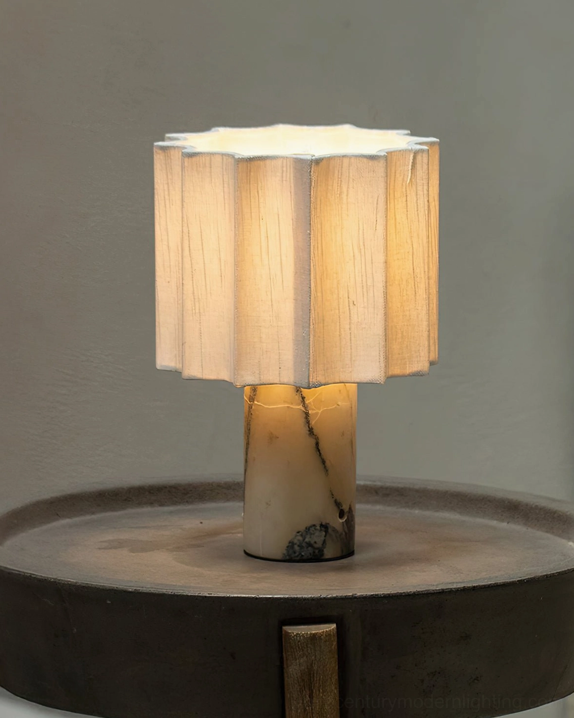 Illuminated Kane cordless lamp on wooden side table, warm glow from pleated beige fabric shade and dark-veined marble base