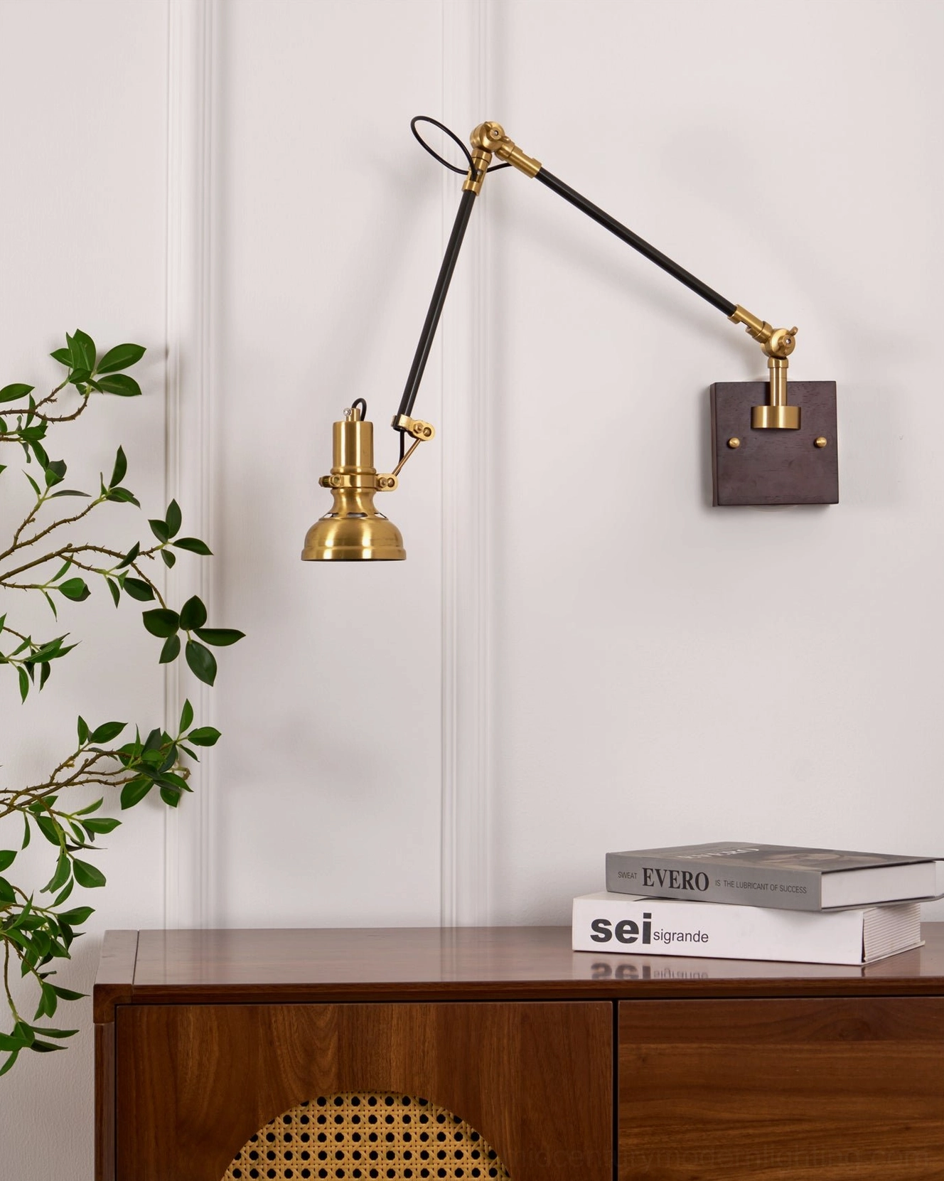 Kane Swing Arm Wall Lamp in minimalist room with stacked books and foliage styling