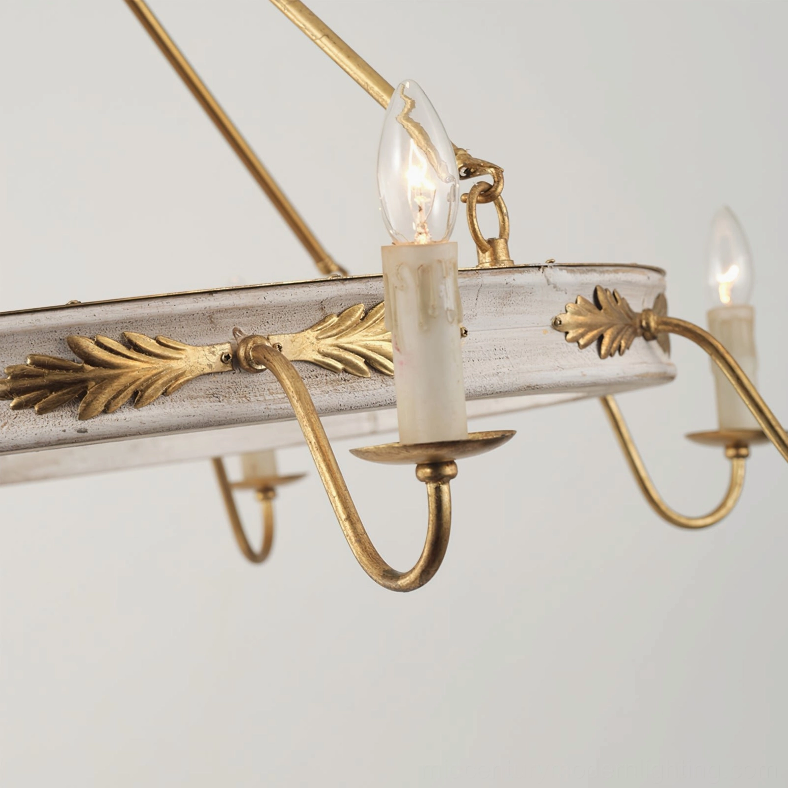Kayleigh chandelier frame and lamp arm detail, showcasing gilded acanthus leaf trim, distressed white circular frame, and candle-style bulb socket