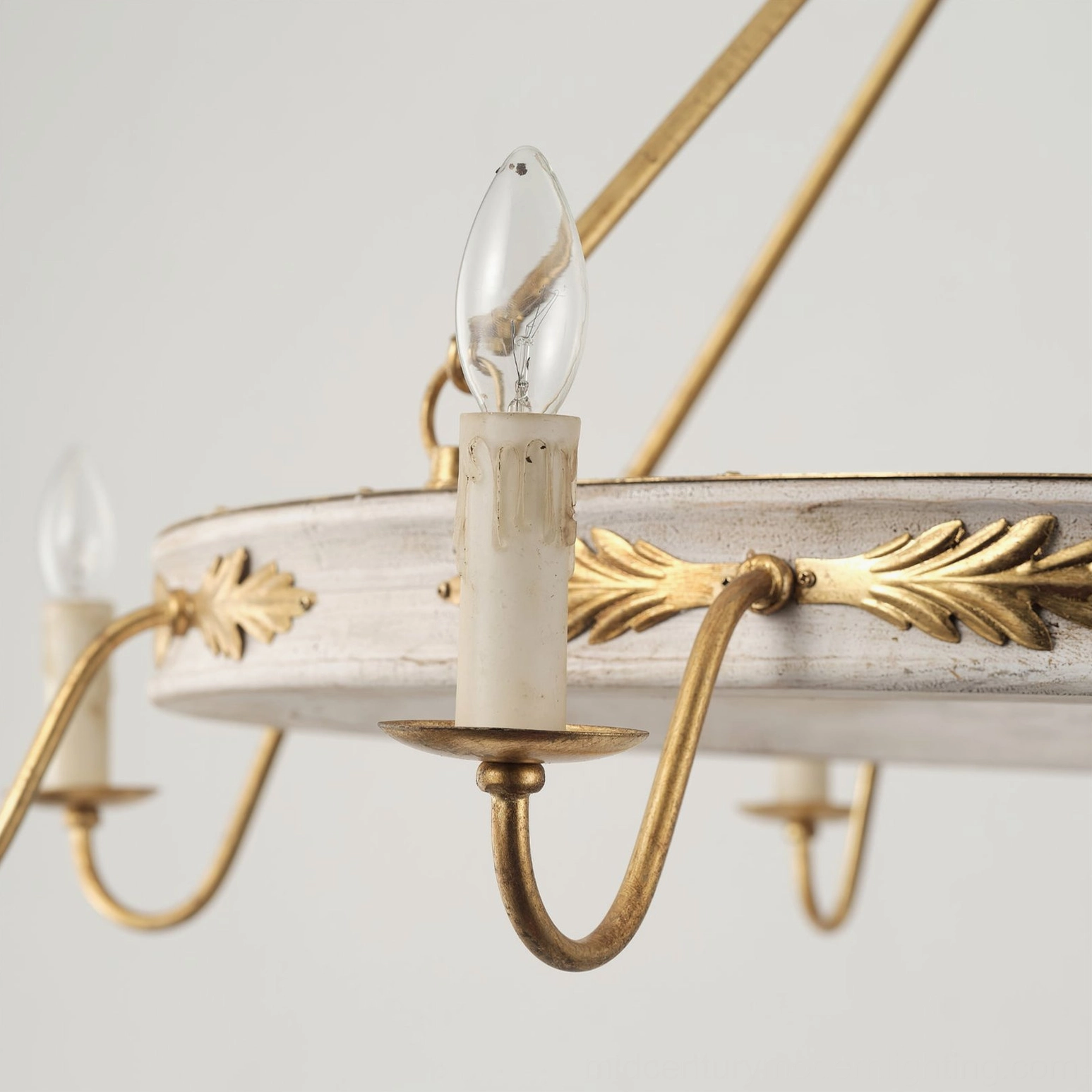 Close-up detail of Kayleigh chandelier candle holder arm, showing curved gold metal construction and distressed white lamp ring with ornamental leaf accents