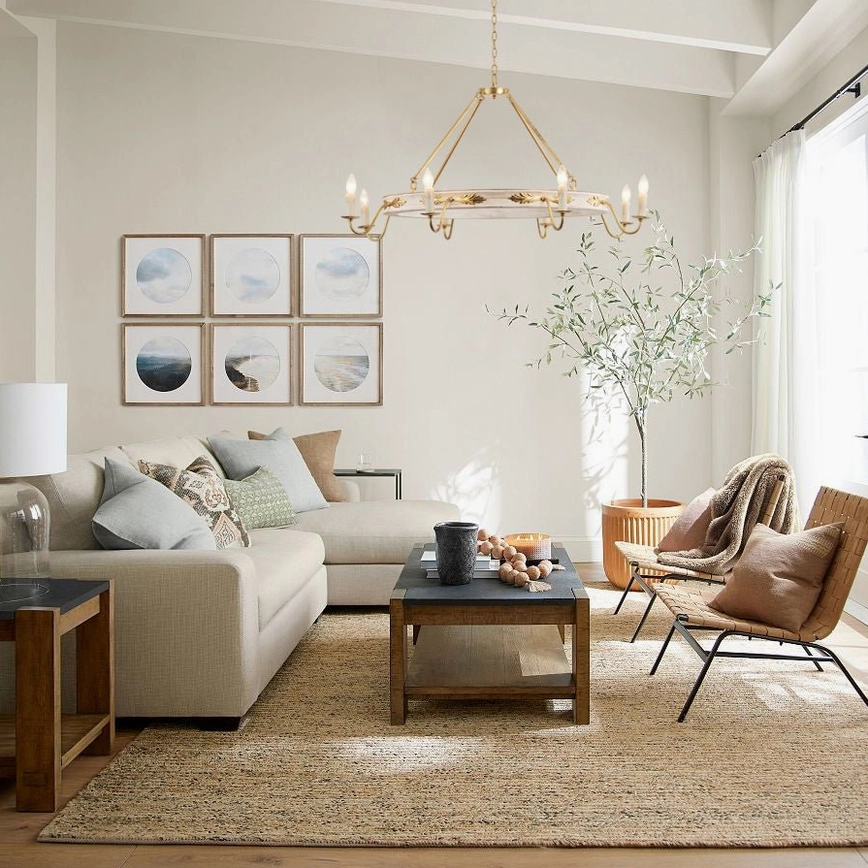 Kayleigh 8-head chandelier installed in modern farmhouse living room above seating area with gallery wall, area rug, and potted plants