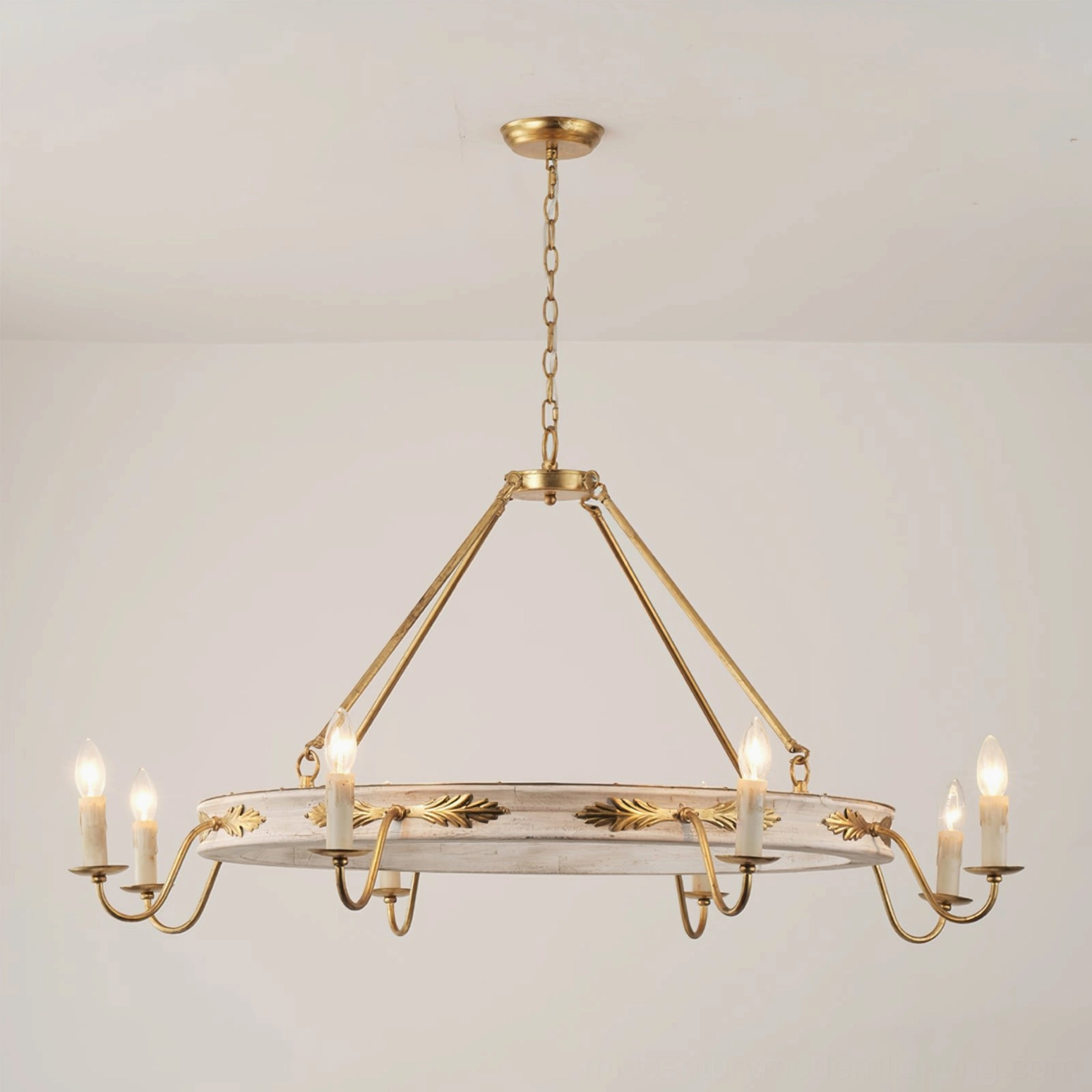 Side profile of Kayleigh chandelier with brass suspension chain, gilded acanthus leaf decorations, and distressed white circular frame against off-white background