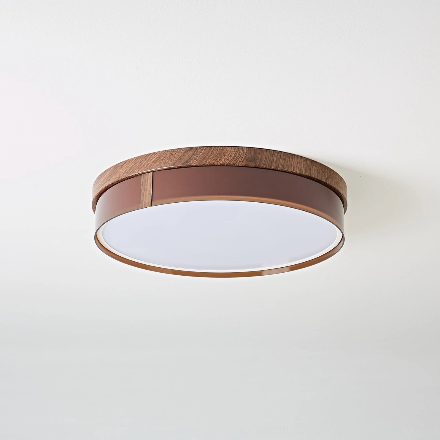 Kelsey round flush mount ceiling light close-up, unlit matte diffuser panel with brown wood-grain trim against white wall