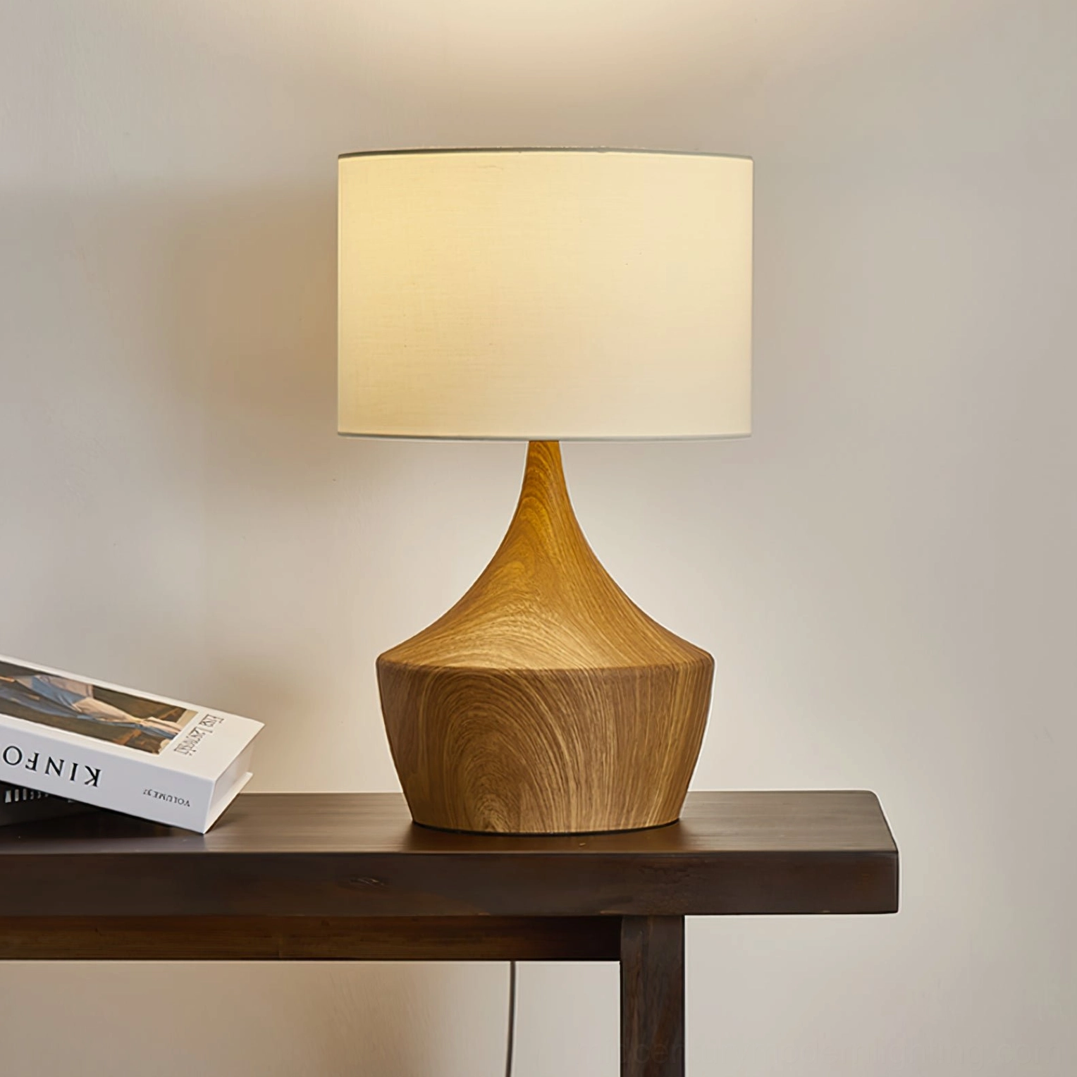 Kendra table lamp lit three-quarter view on decorated console with warm inviting light