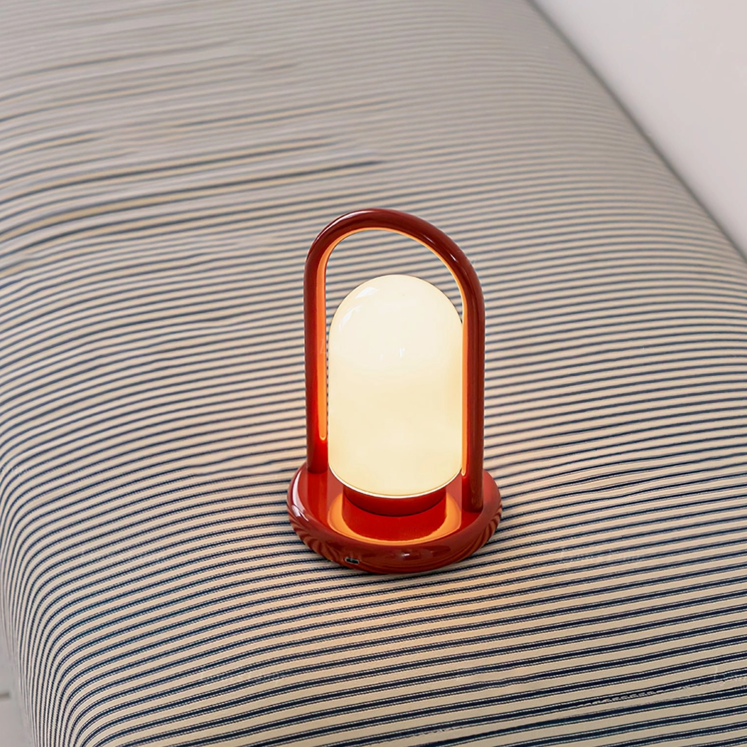 Kero table lamp illuminated on bed surface, showing frosted glass shade and warm ambient light