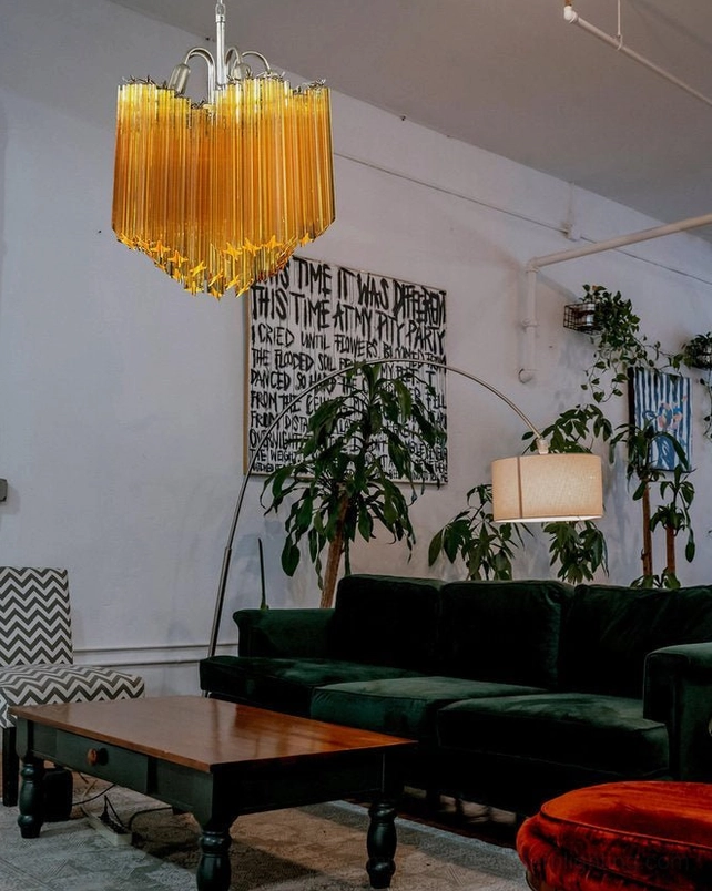 Kite amber glass chandelier in eclectic bohemian living room with green velvet sofa