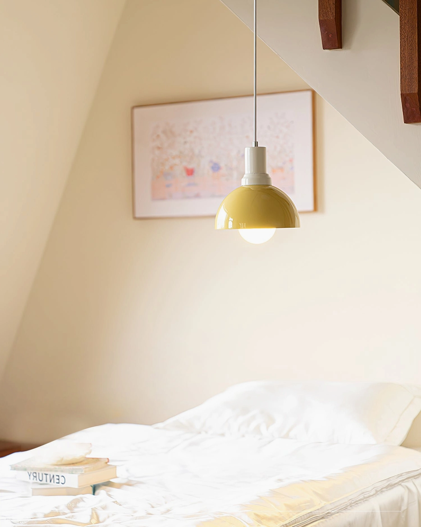 Kleine yellow dome pendant fixture above linen bedding – attic staircase bedroom with stacked literature and minimalist furnishings