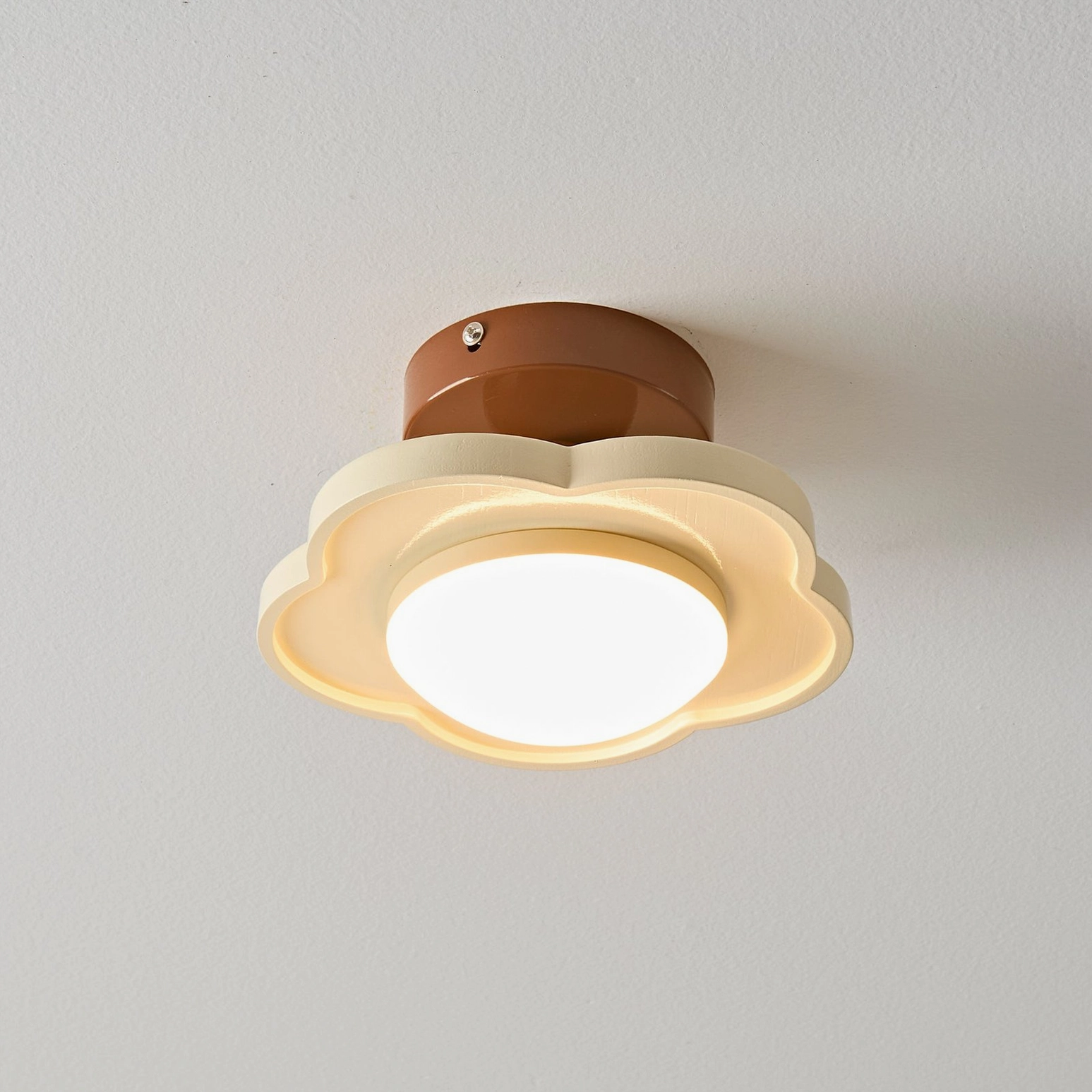 Laguna ceiling lamp detail shot showing brown metal base, warm light illumination, organic flower-like form