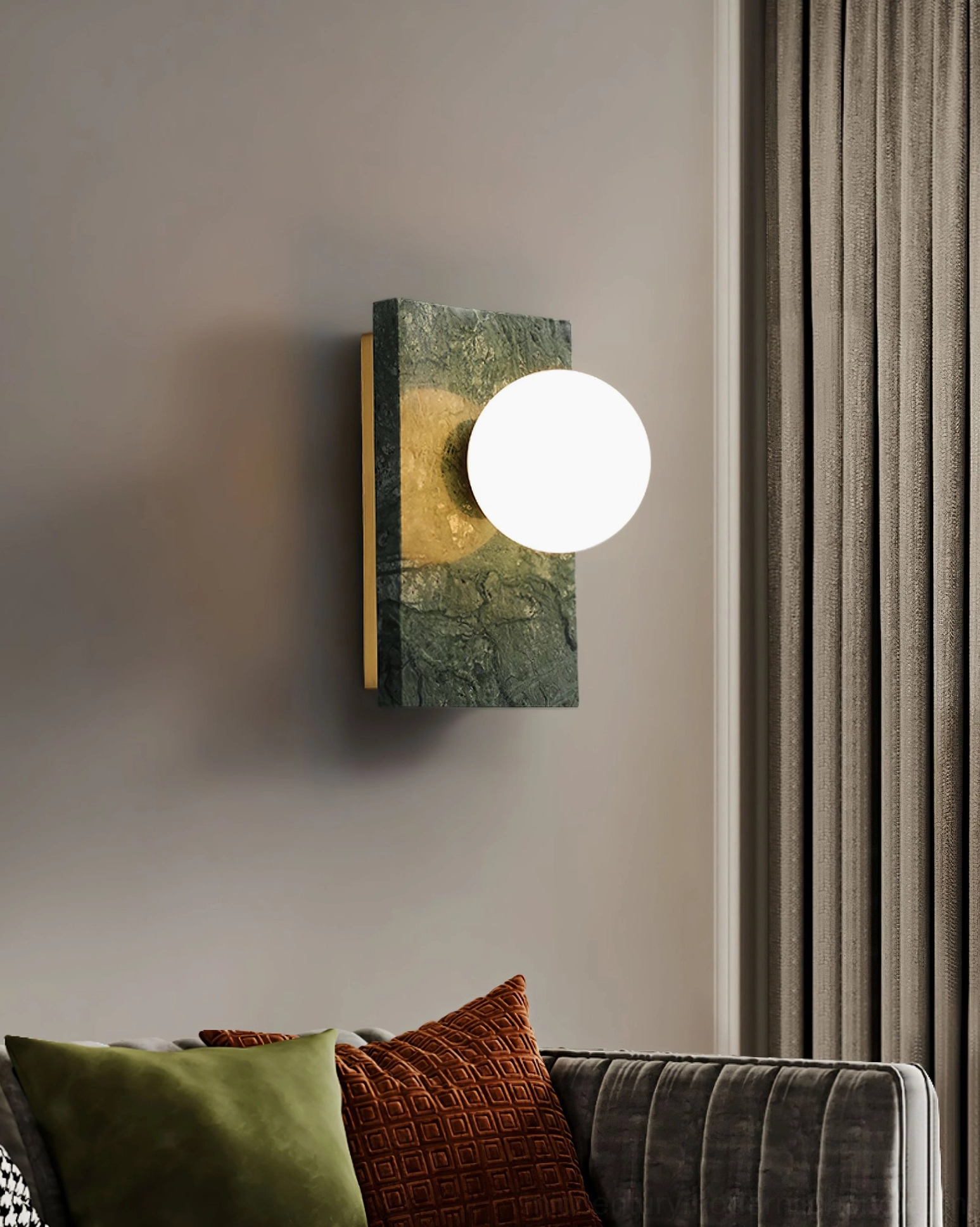 Eye-level view of green marble Lan wall sconce with brass accents mounted above modern sofa