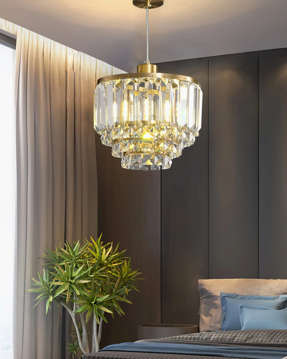 Tiered crystal brass pendant fixture above bed with blue bedding modern bedroom lighting