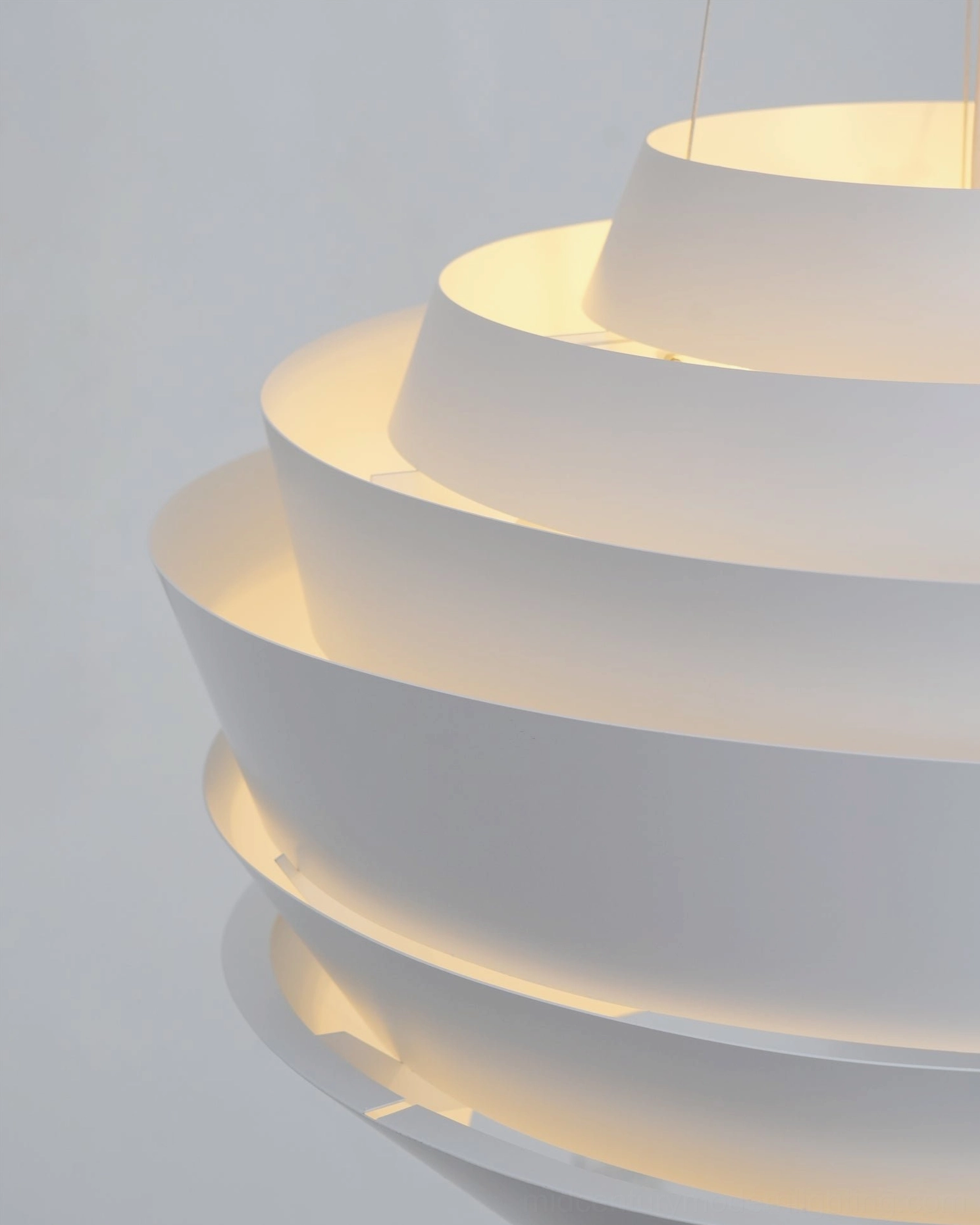 Low angle close-up tiered pendant light warm ambient glow between layers matte white
