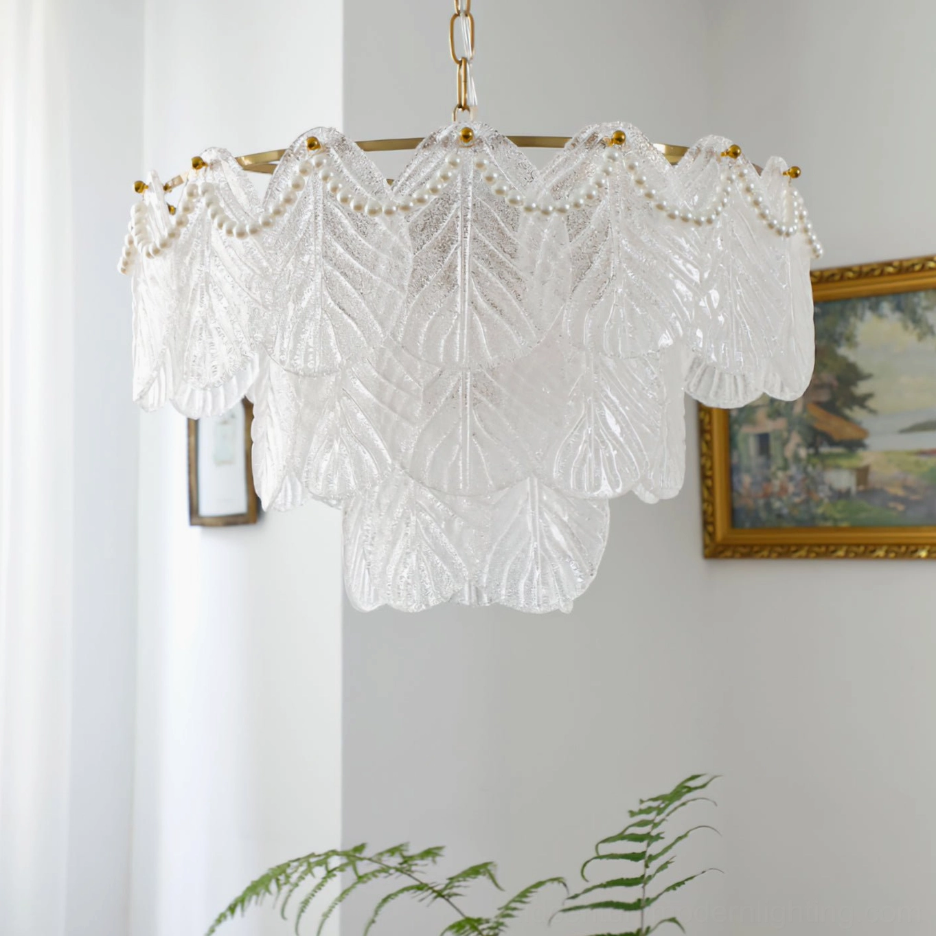 Side profile of tiered frosted glass leaf chandelier with brass suspension chain in minimalist white living room, showcasing elegant geometric silhouette