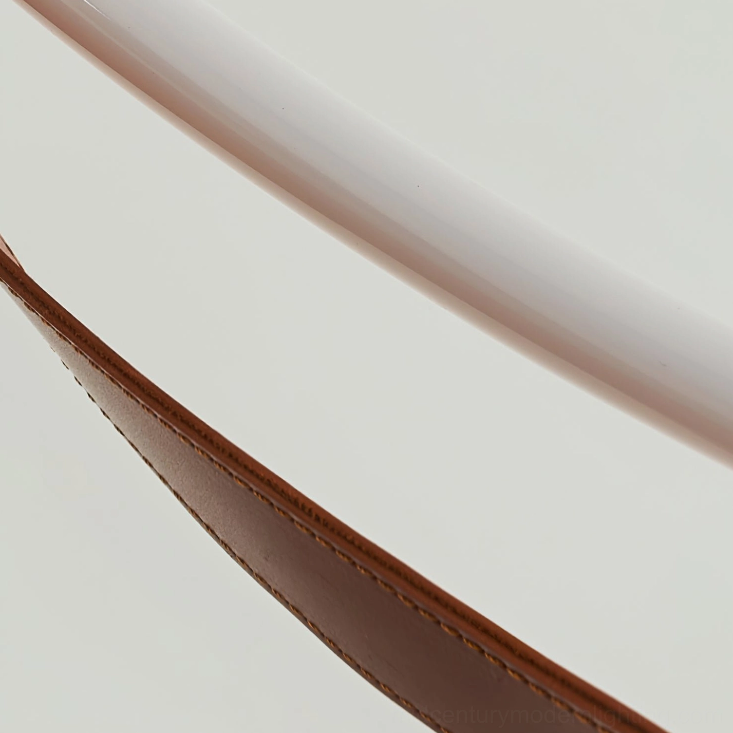 Close-up detail of tan leather strap showing hand-stitched seams and natural leather texture on white background