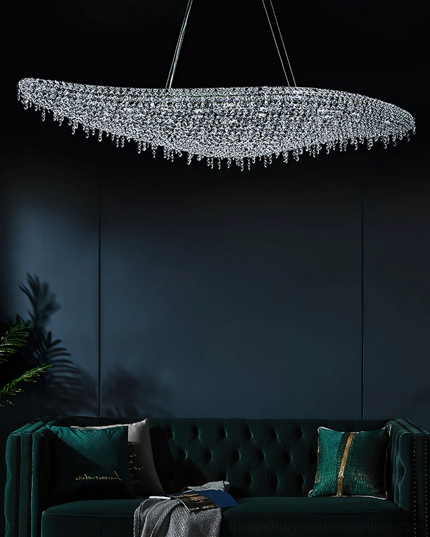 Cool-toned leaves crystal chandelier overhead installed in dark luxury living room above emerald velvet sofa