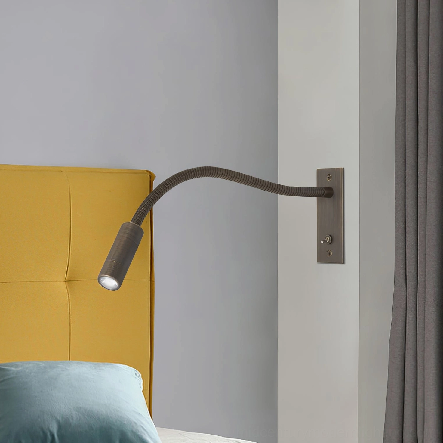 Bronze gooseneck LED reading lamp mounted over yellow headboard in contemporary bedroom setting