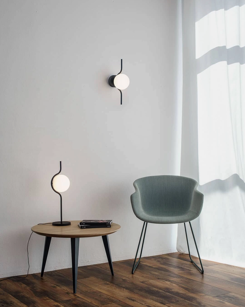 Levita table lamp with curved elegant metal stem and frosted glass sphere in contemporary minimalist space