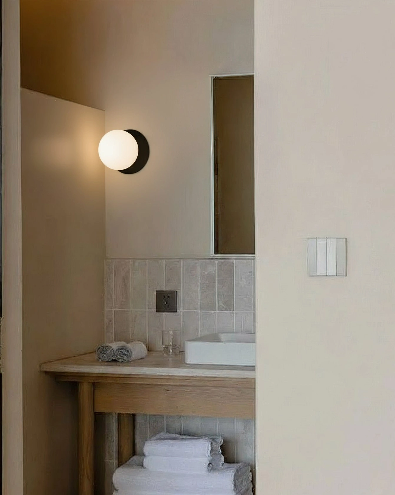 Single Lila black matte wall sconce with clear glass sphere in contemporary bathroom corner