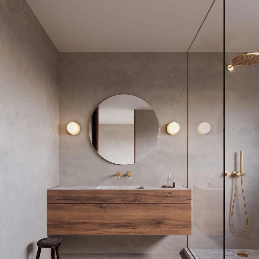 Lila black matte wall sconce lit detail showing warm bulb glow through frosted glass