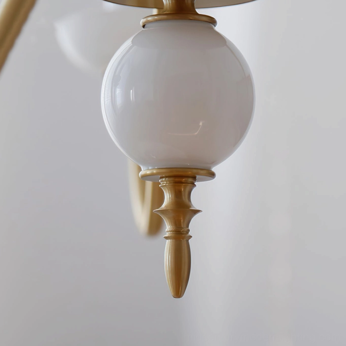 Spherical white ceramic decorator element and polished brass hardware detail on candle chandelier