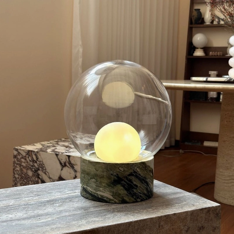 Lilly table lamp glowing with warm light on grey stone bench in modern minimalist interior