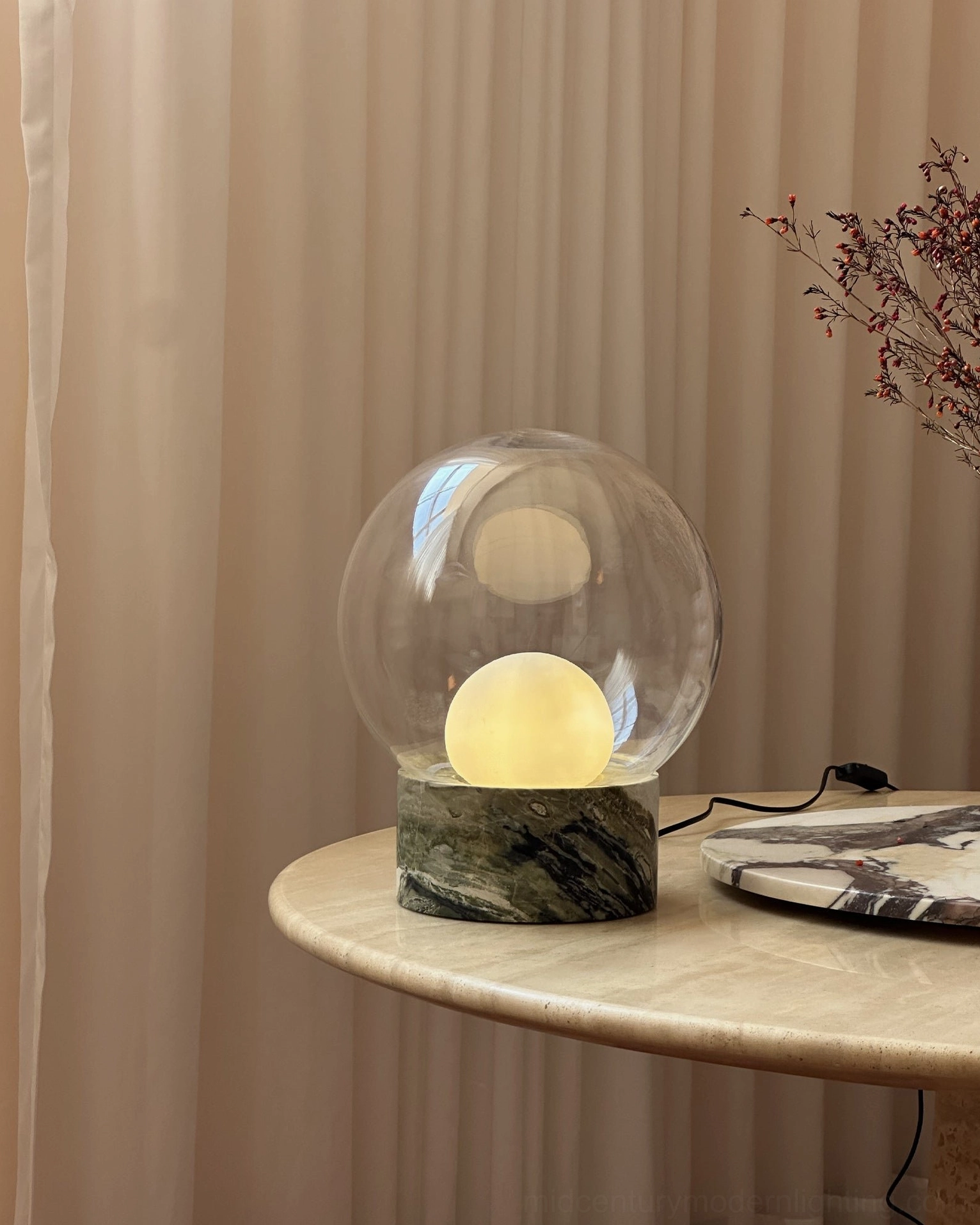 Side profile view of Lilly marble globe lamp with warm lighting on minimalist home table