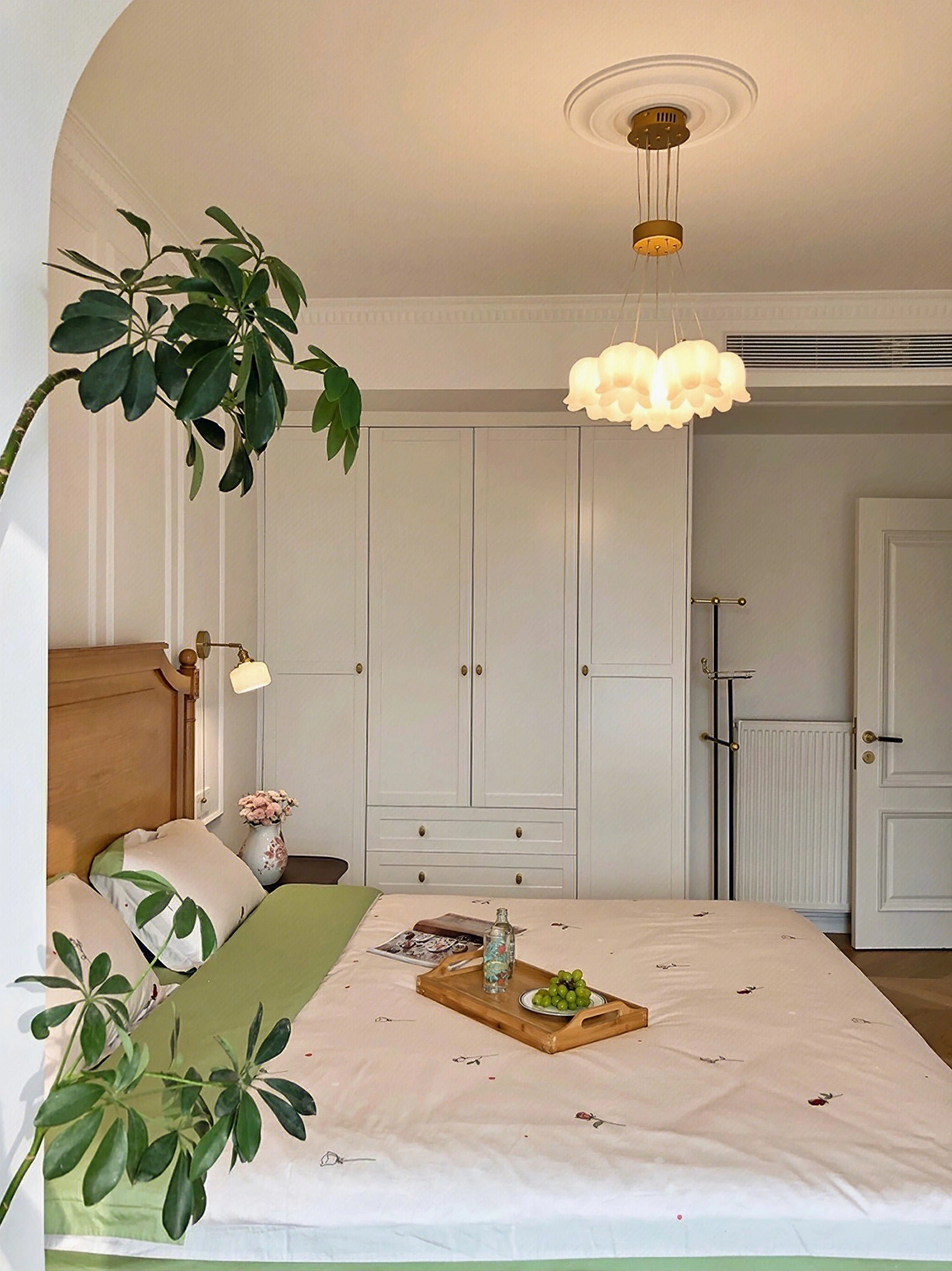 Lily of the valley chandelier installed in French creamy bedroom with warm wood tones and rustic design aesthetic