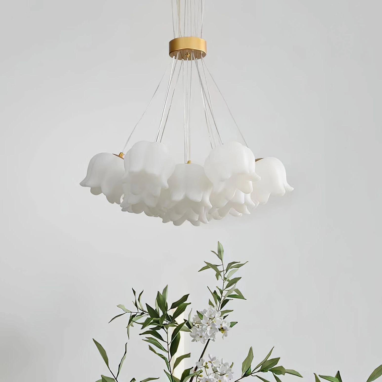 Close-up detail of lily of the valley ceiling chandelier with frosted acrylic flower shades and gold metal hardware in modern interior setting