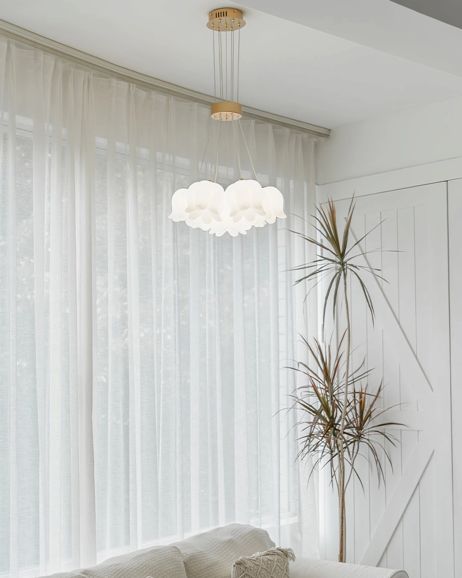 Delicate flower-shaped frosted acrylic lamp shades on lily of the valley chandelier in creamy living room with sheer curtains