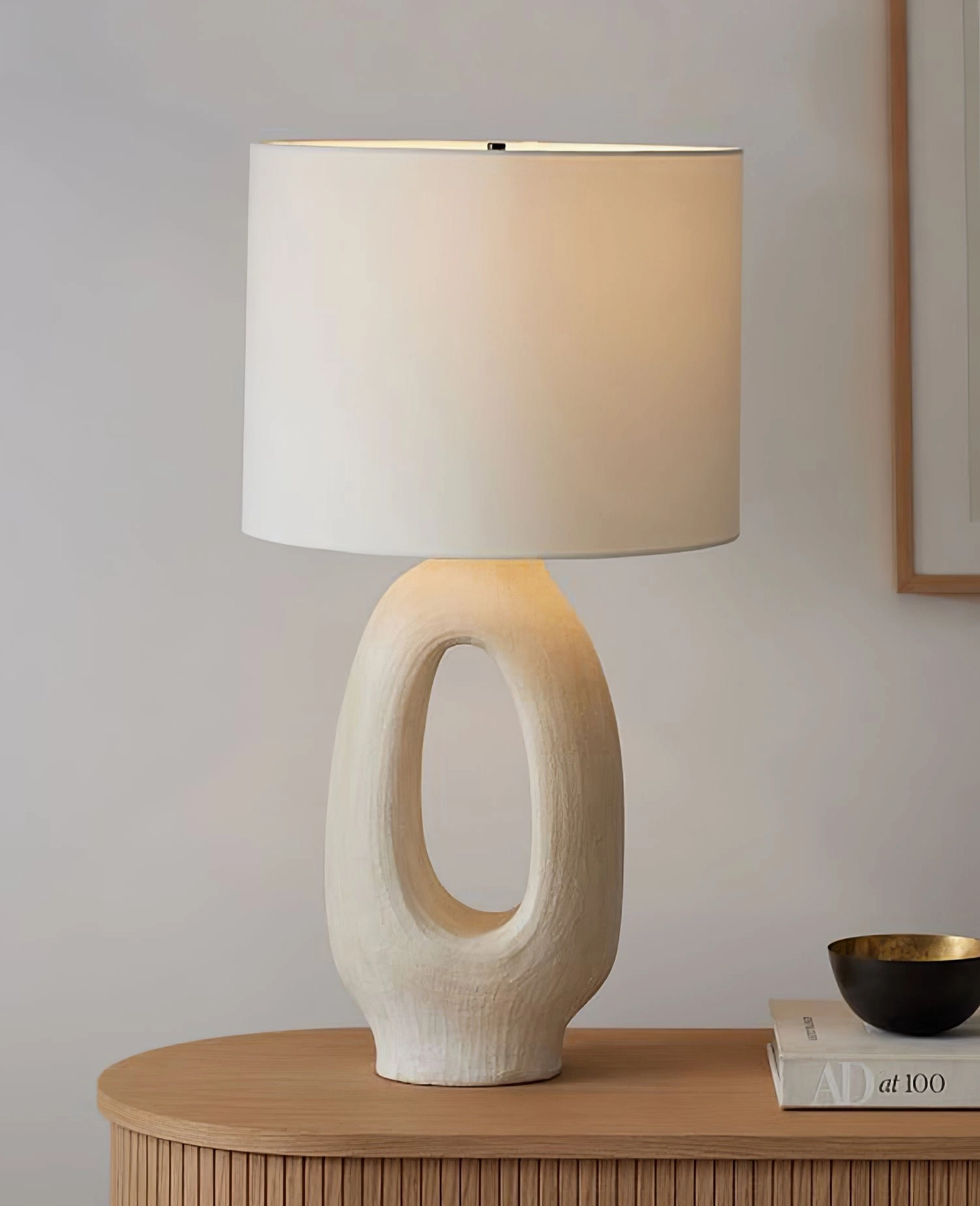 Sculptural table lamp with linen fabric shade diffusing warm LED light through organic modern base