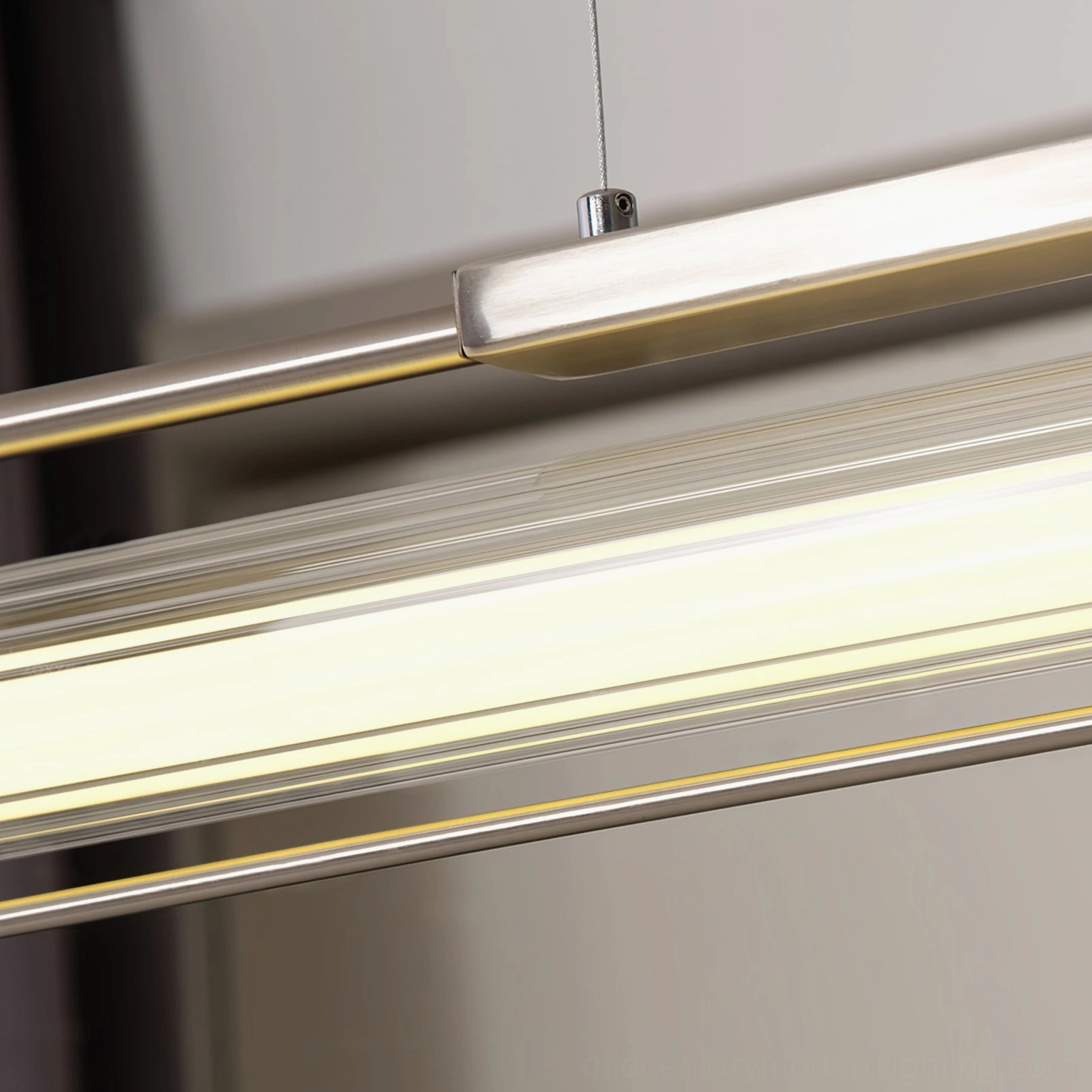 Side view close-up of illuminated Lirna linear LED chandelier with metallic frame and ribbed shade detail
