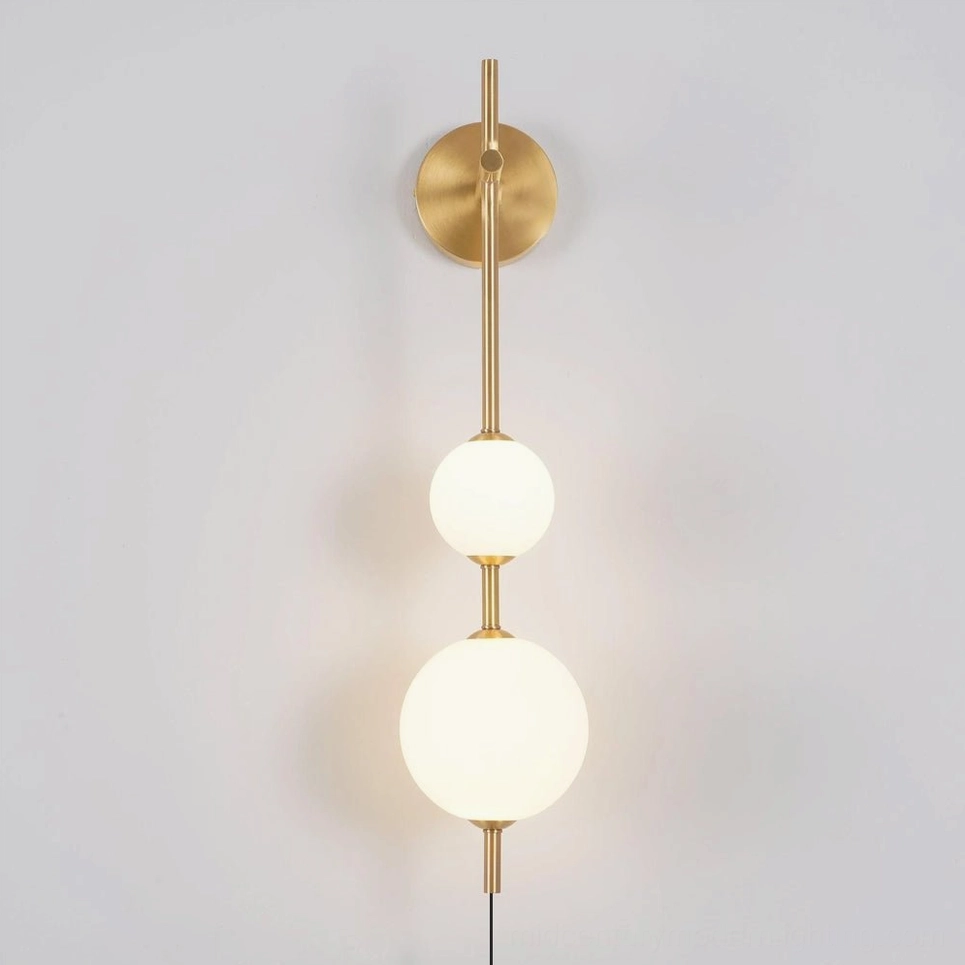 Modern brass globe wall lamp lit with warm 3000K LED light, two-tier frosted glass spheres, minimalist design
