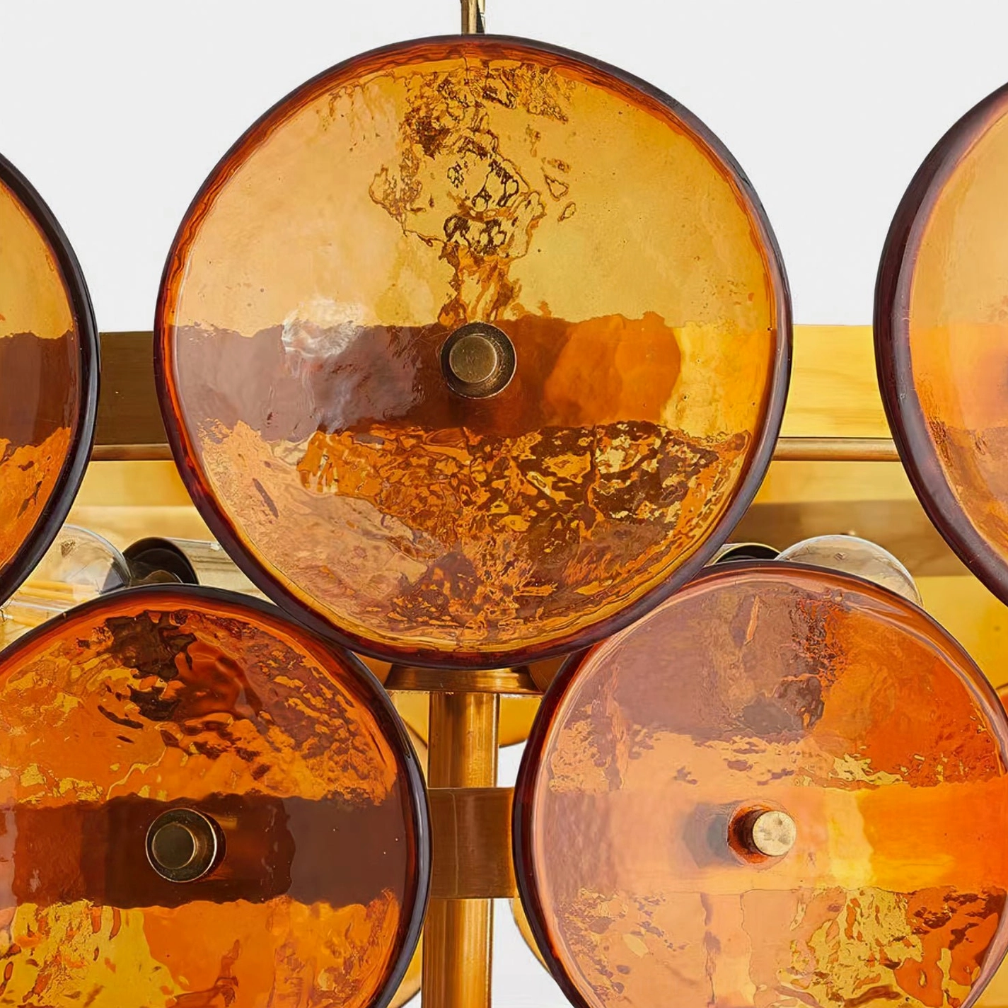 Close-up macro detail of amber orange rippled Murano-style glass discs on Lorenzo chandelier