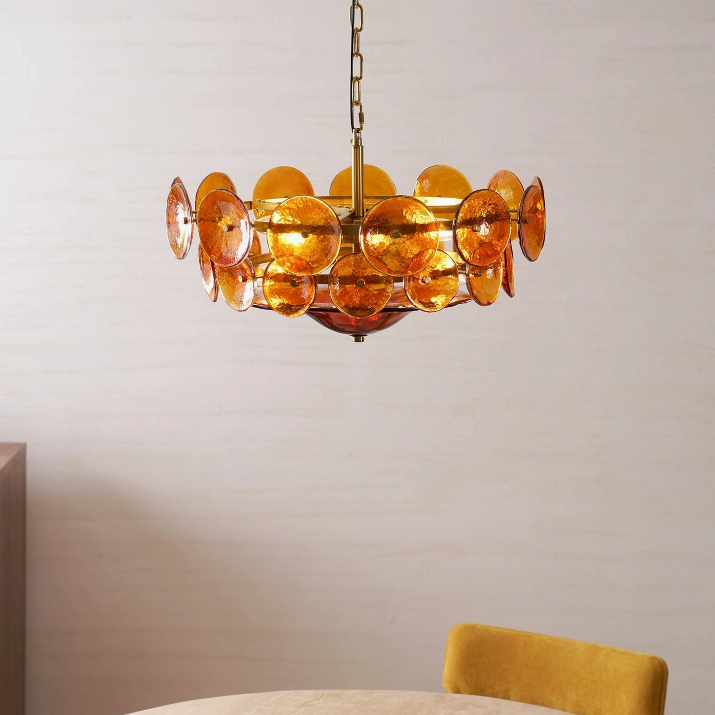 Amber orange Lorenzo chandelier showing warm light cast through rippled glass discs at dusk