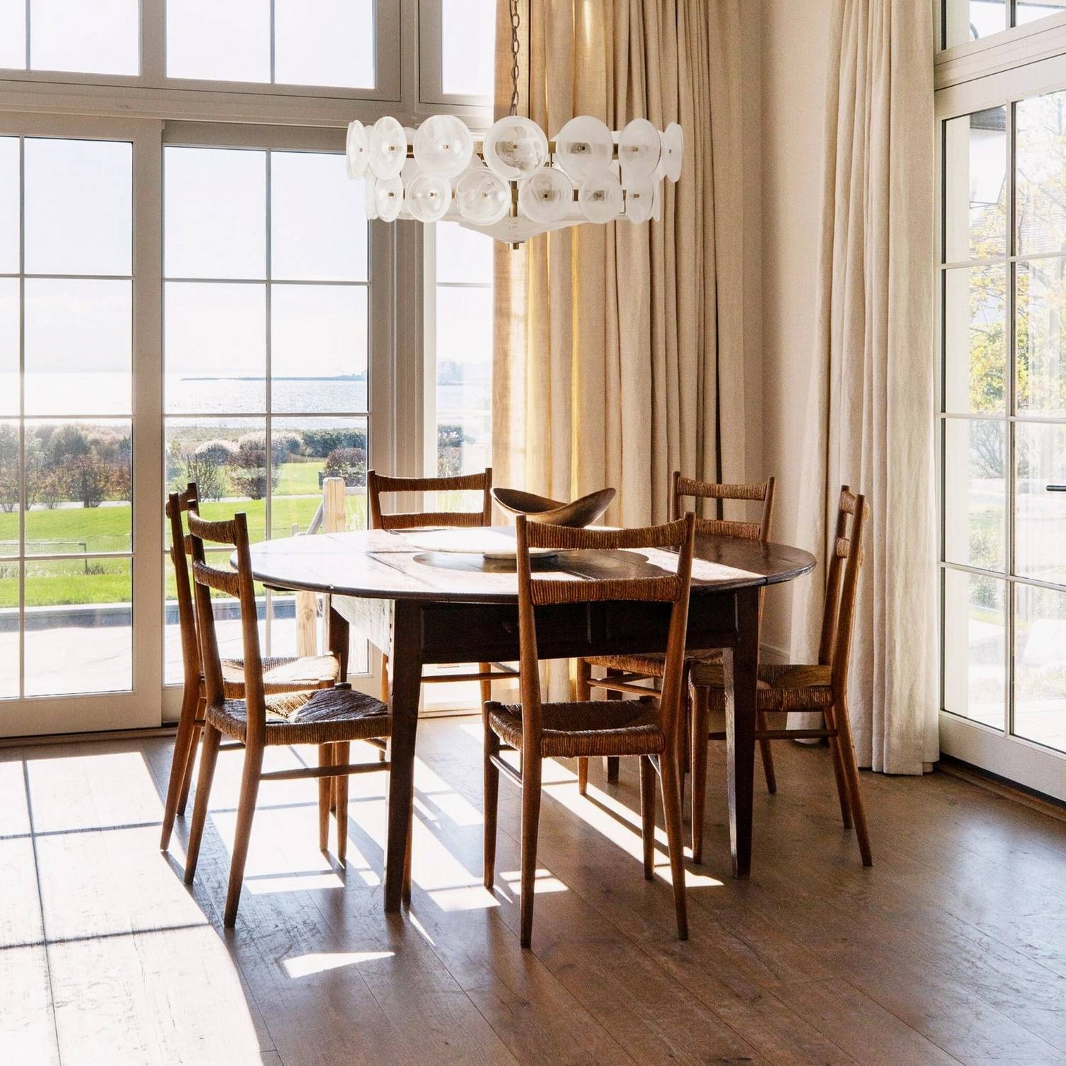 White soft Lorenzo glass disc chandelier in contemporary dining room with natural light and minimalist design