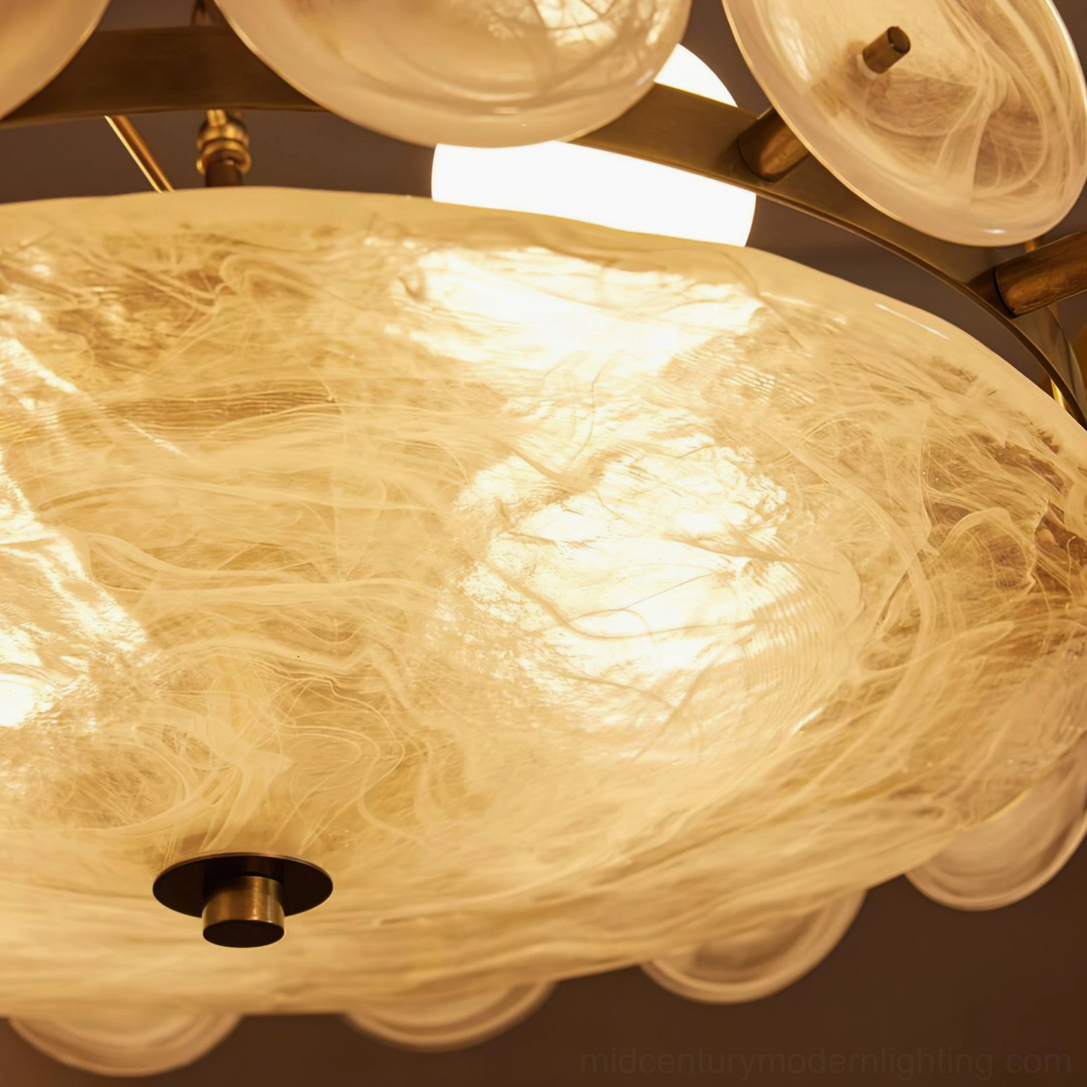 Bottom-up macro view of white scalloped edge marbled glass shade on Lorenzo chandelier with warm glow